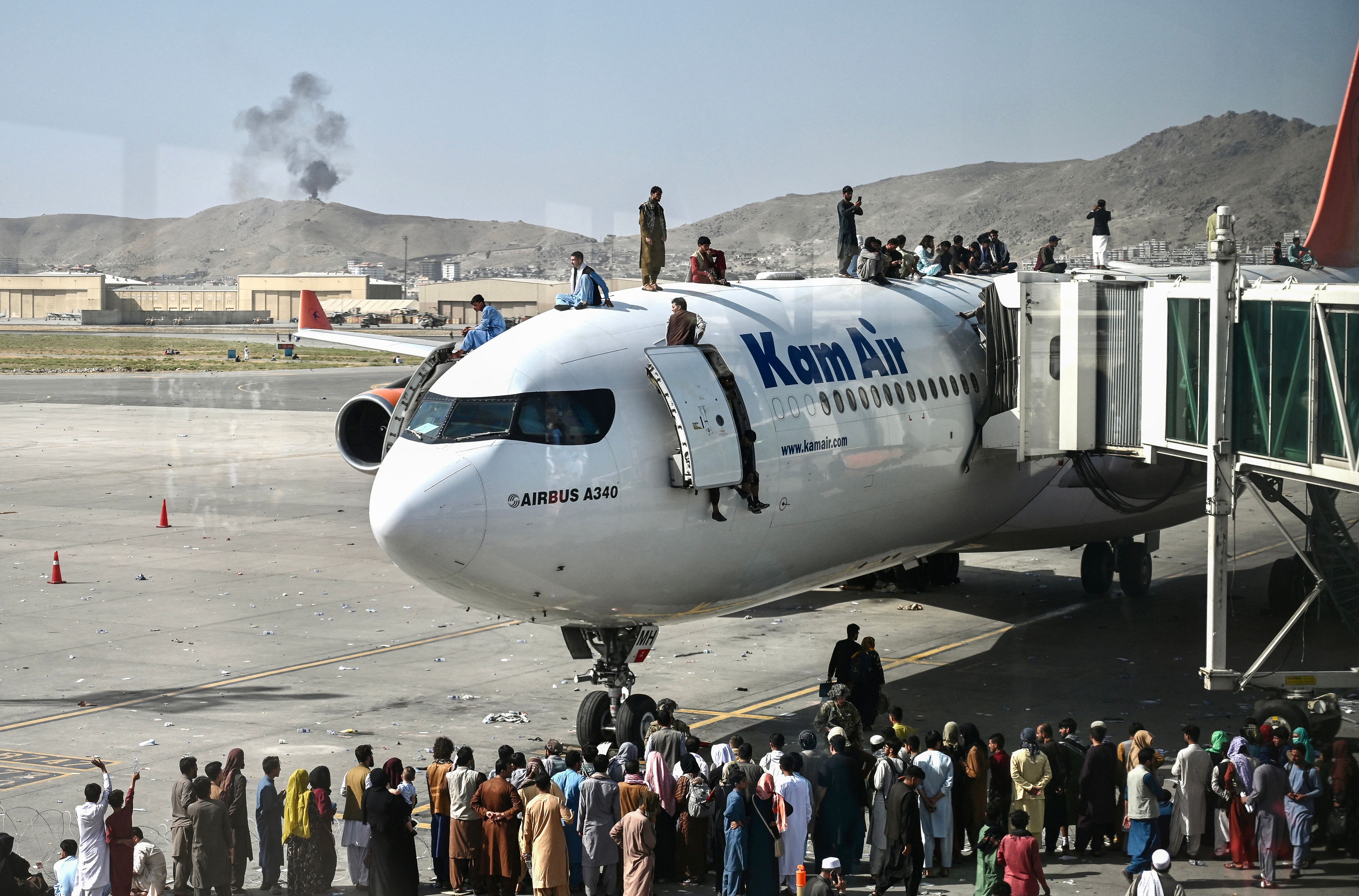 Afghans climbing on top of plane