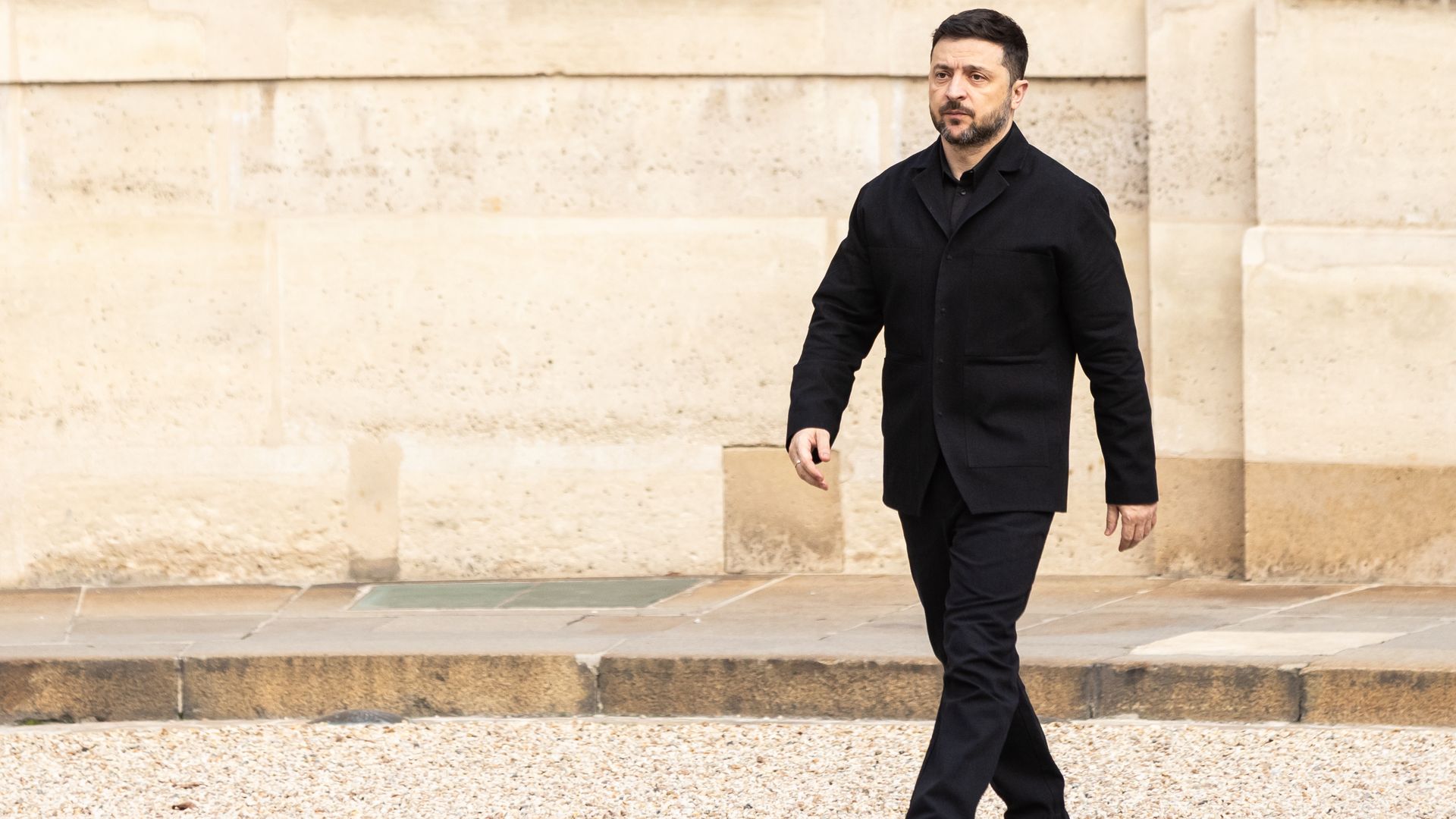 a man dressed in all black is walking Men's Black Safari Suit with Textured Utility Jacket and Matching Trou