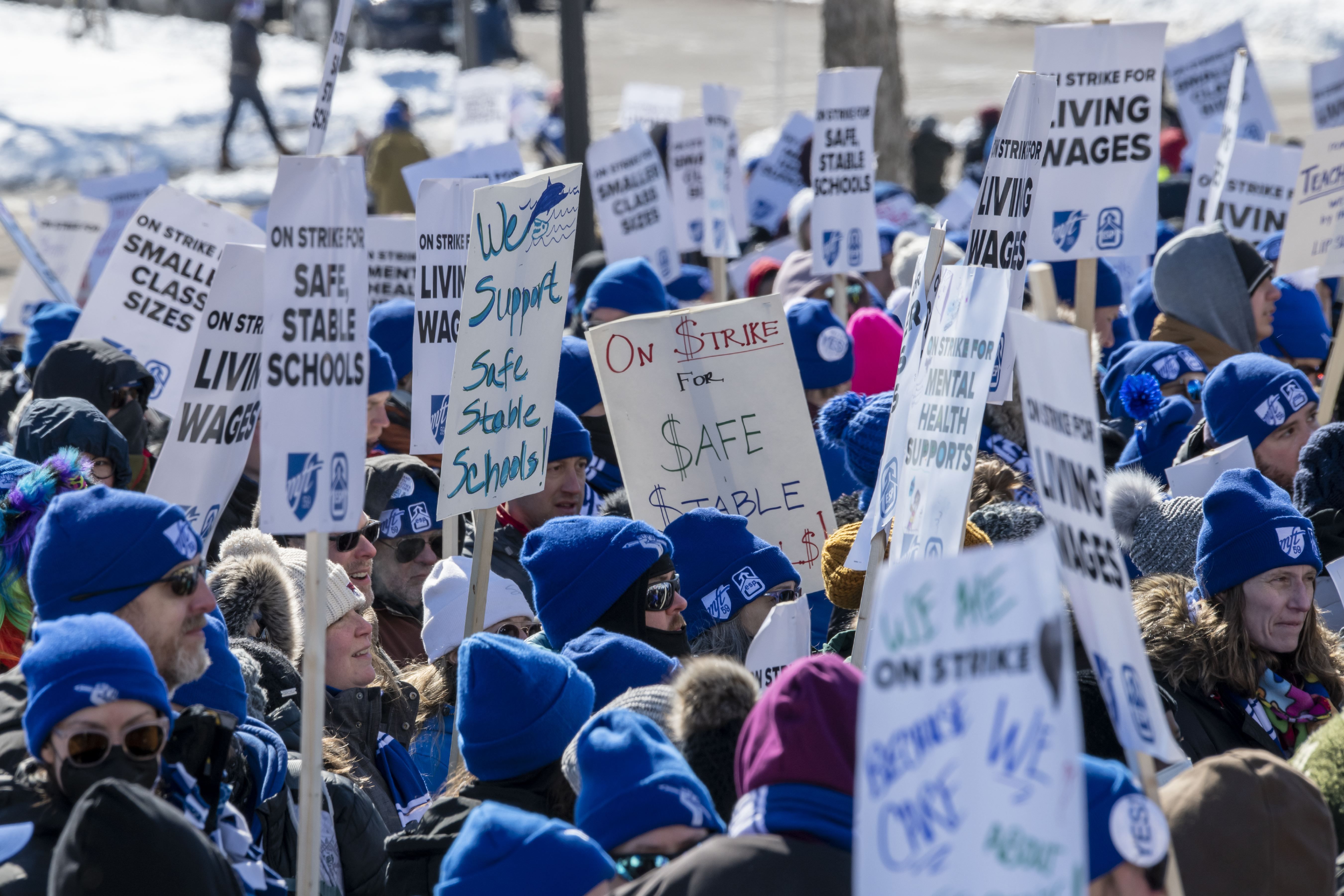 A group of people holding picket signs with slogans about supporting Minneapolis teachers.
