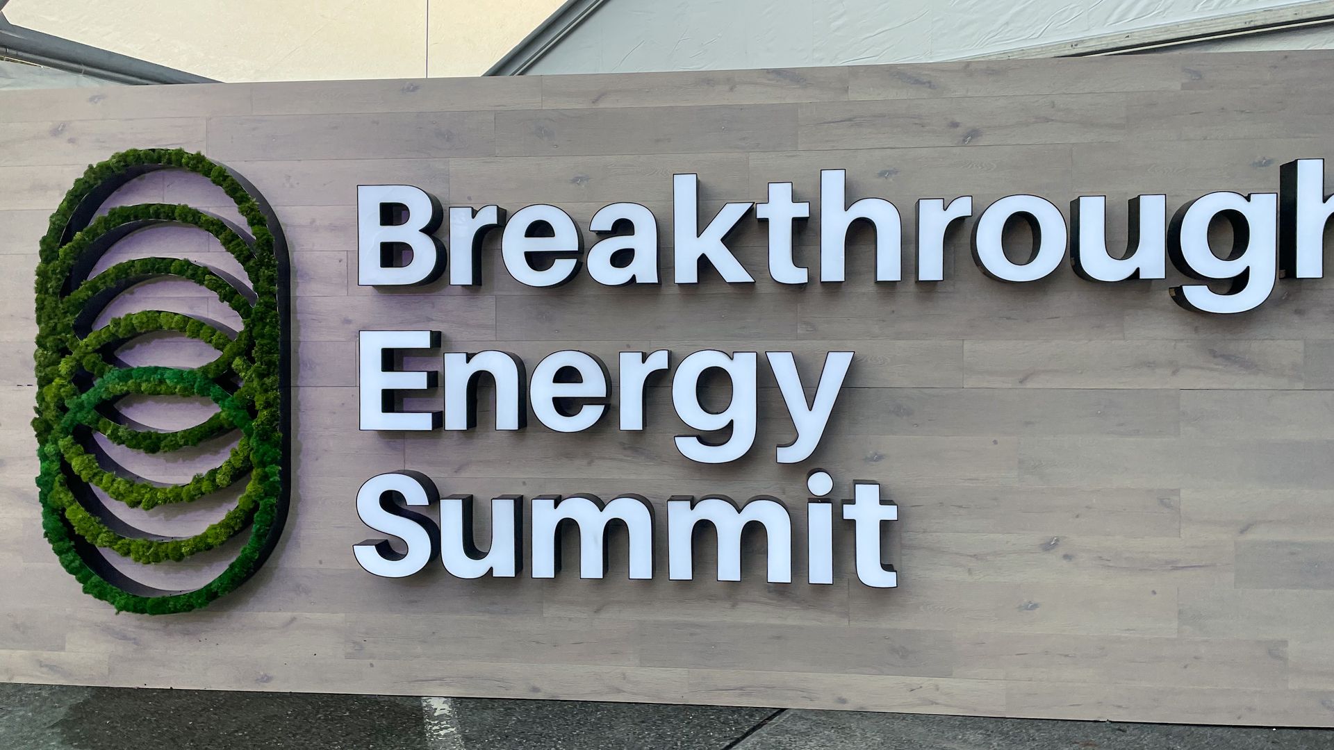 A photo of a glowing sign that says "Breakthrough Energy Summit" against a hazy orange sky.