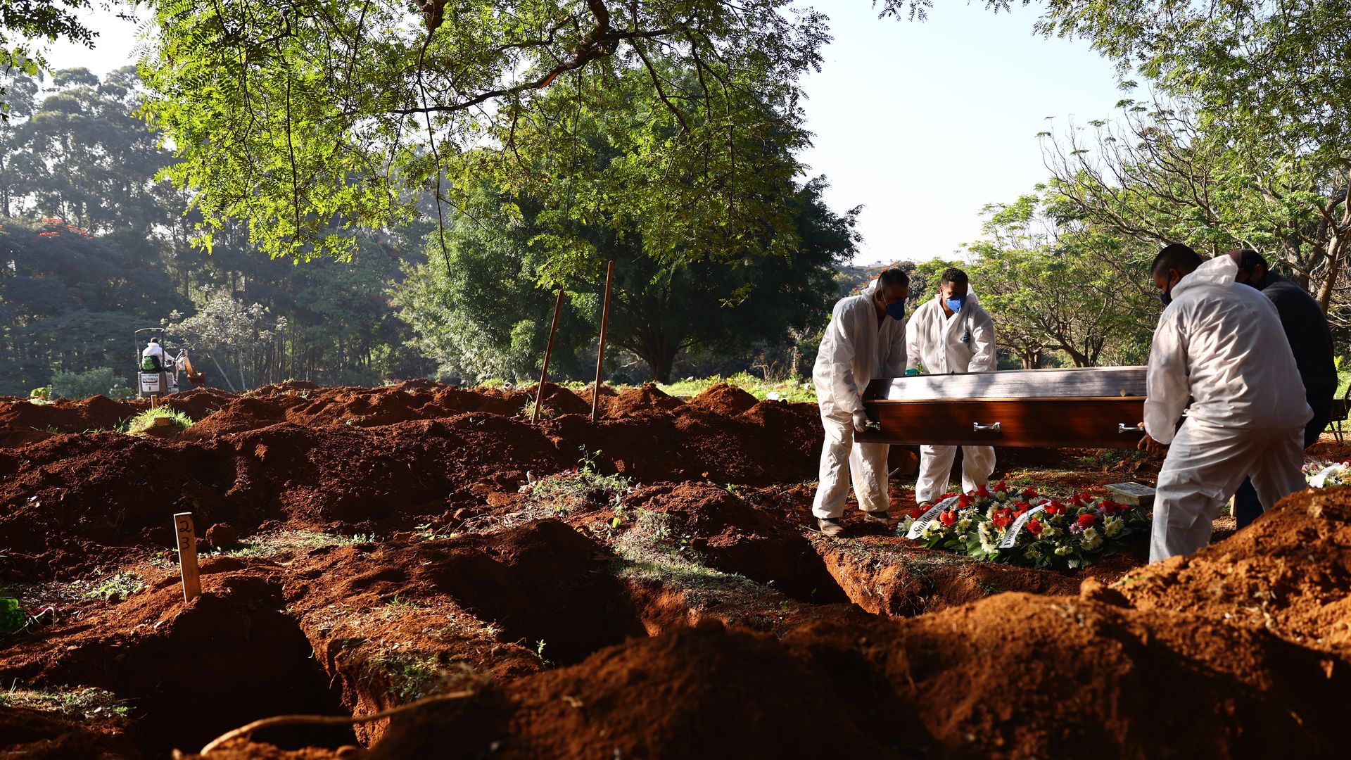 Cemetery workers in protective suits carry the coffin of a COVID-19 victim to be buried at Vila Formosa cemetery