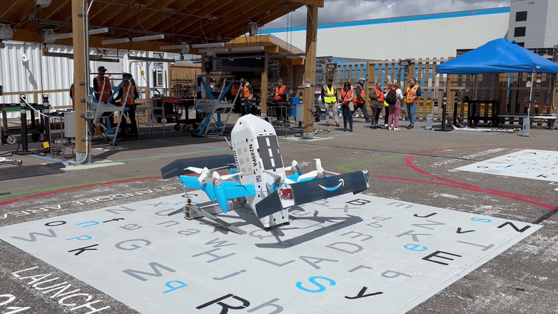 a drone takes off from a concrete pad and flies through the sky. it looks like the size of a small trashcan