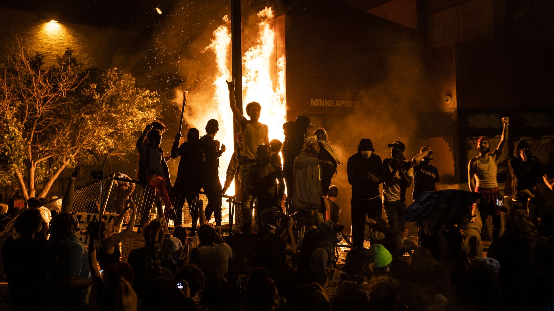 Protesters cheer as the Third Police Precinct burns behind them on May 28, 2020 in Minneapolis