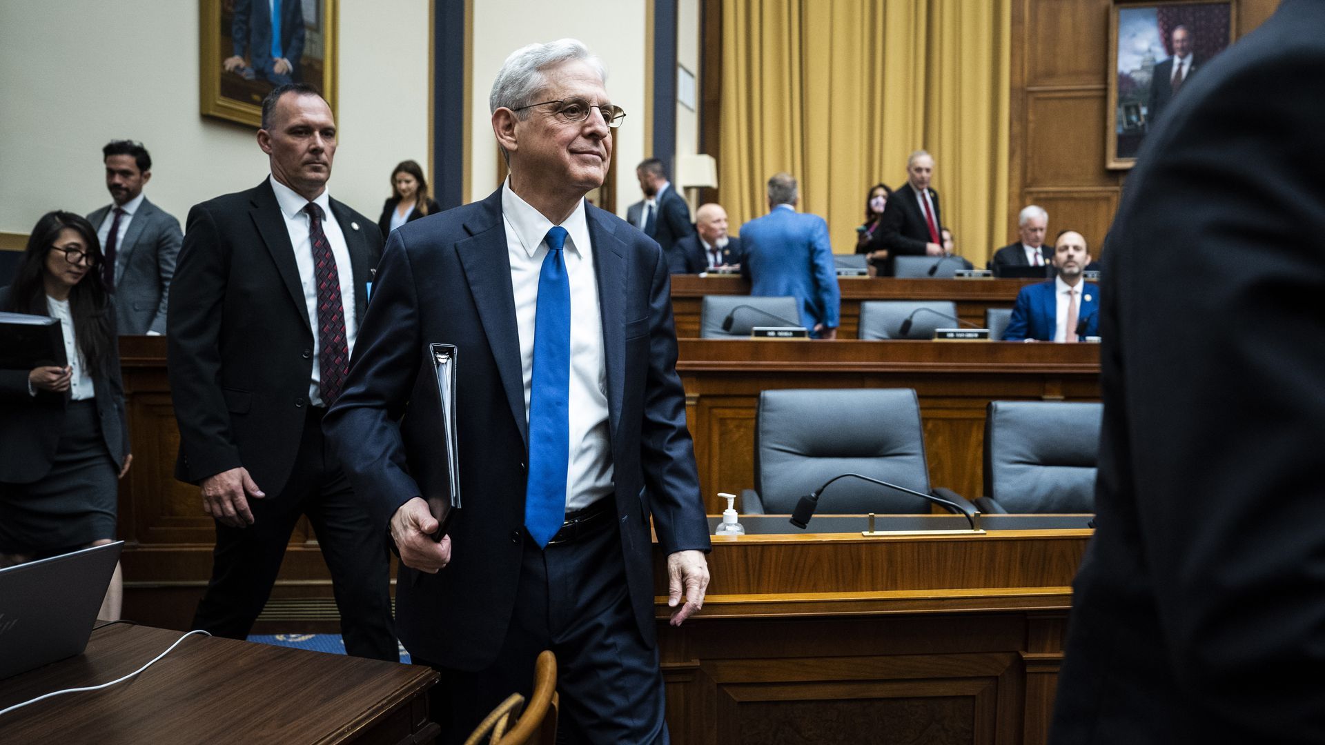 Merrick Garland carries a notebook into a hearing.