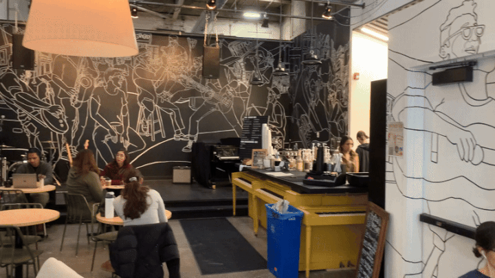 GIF of a coffee shop decor, with people sitting in chairs. 