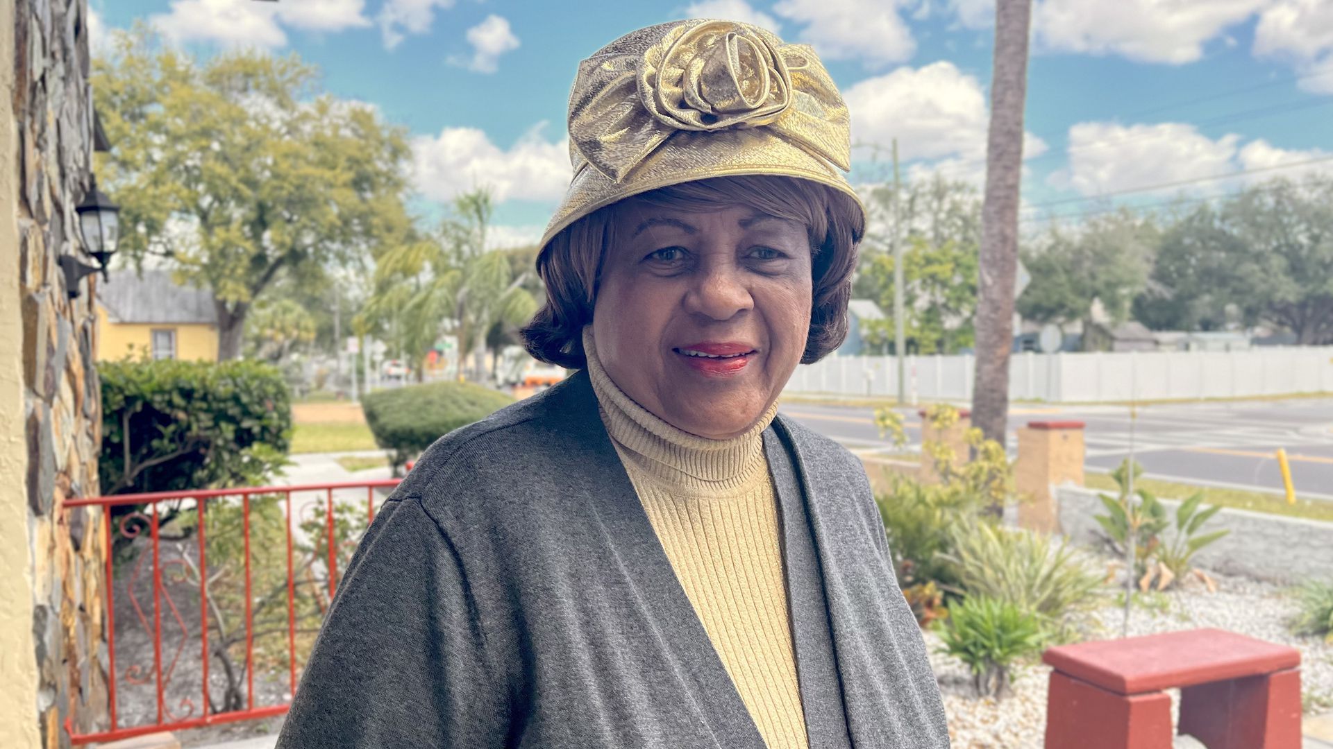 Chloe Coney wears a gray sweater over a yellow turtleneck with a yellow hat.