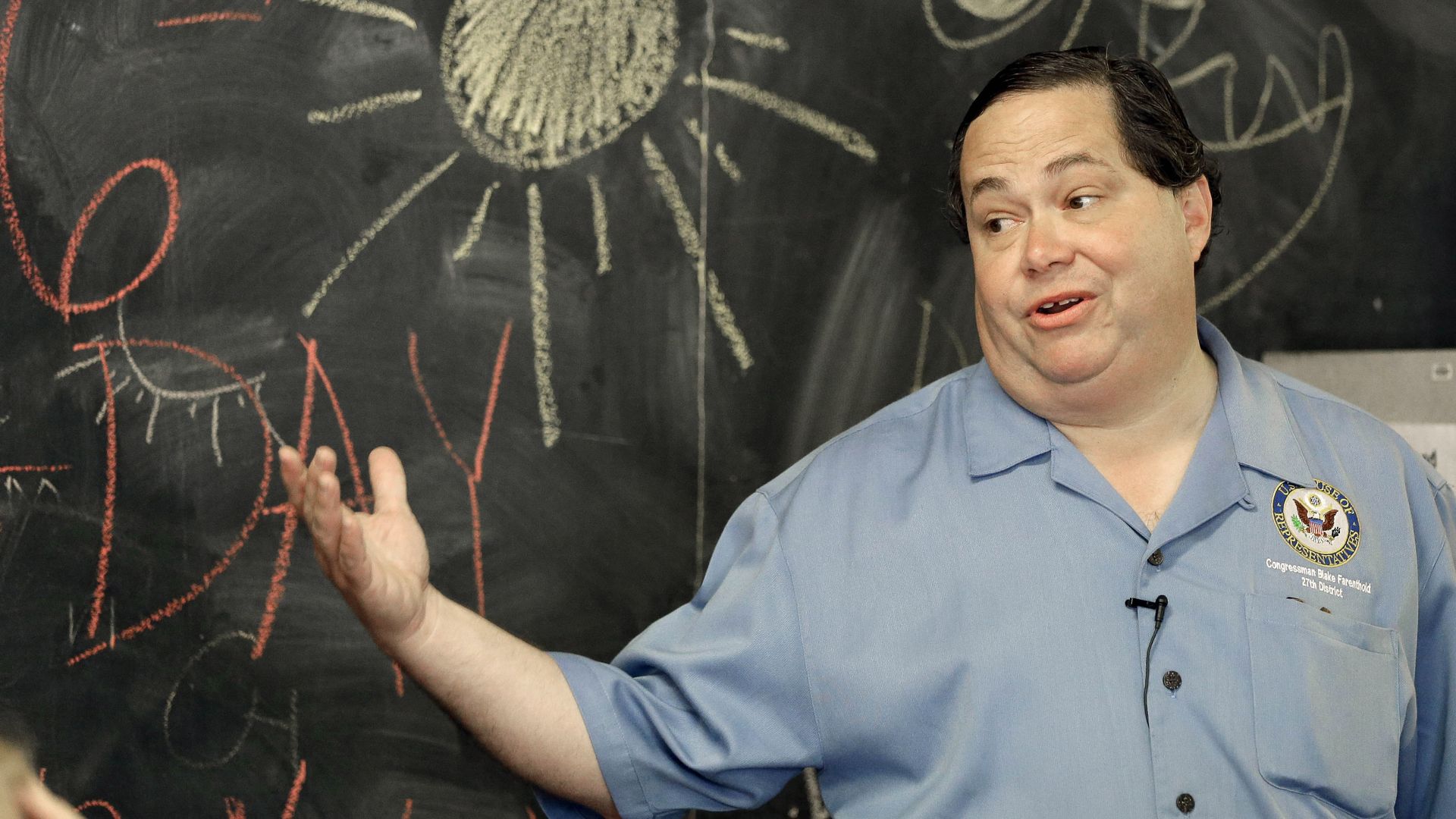 Rep. Blake Farenthold in front of a chalkboard with a yellow sun drawn on it with chalk. 