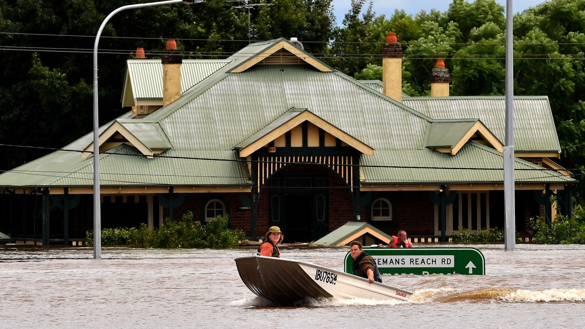 Residents steer boats around flooded houses