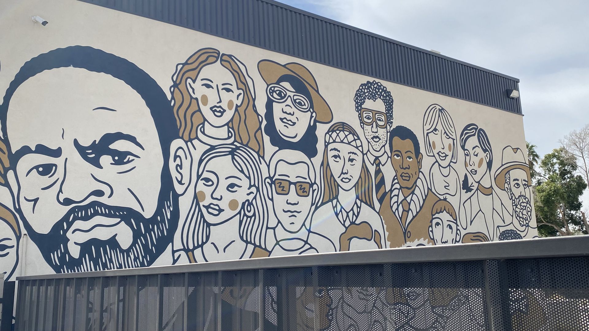 A mural depicting a large human head and cluster of smaller people in a crowd. 