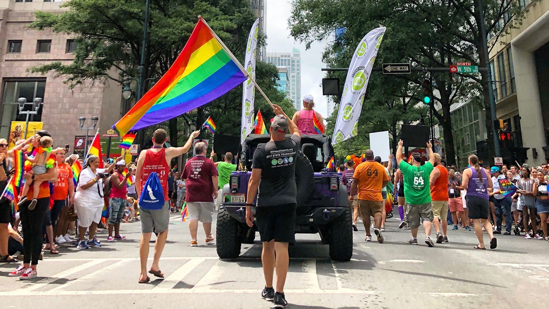 photo of people holding pride flags and walking down the street