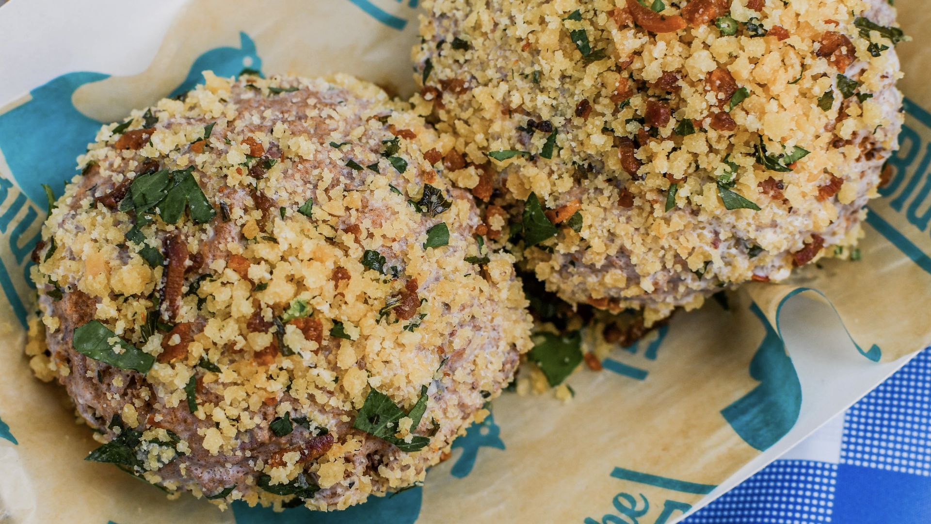 Two biscuit-style doughnuts stuffed with shredded chicken and drizzled with Buffalo sauce icing and bacon bits.