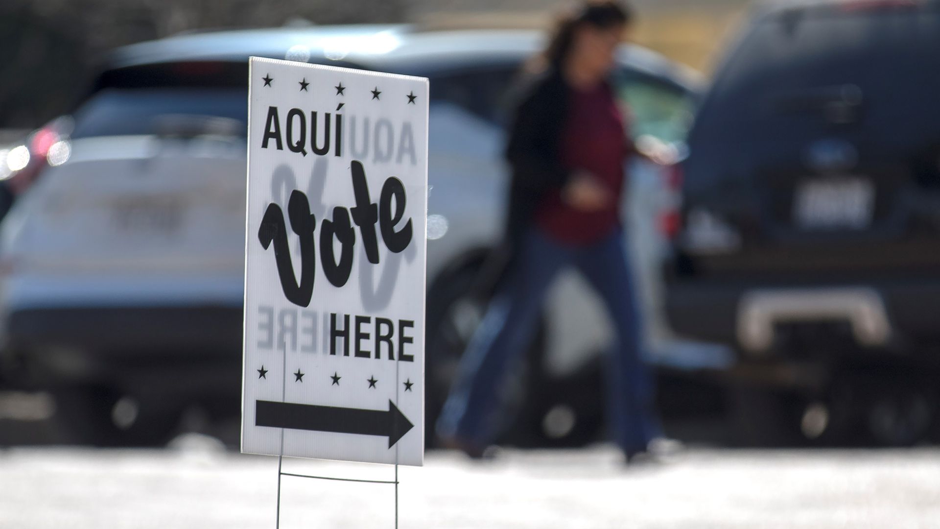 Photo of a sign that says "Aqui, vote here" in a parking lot