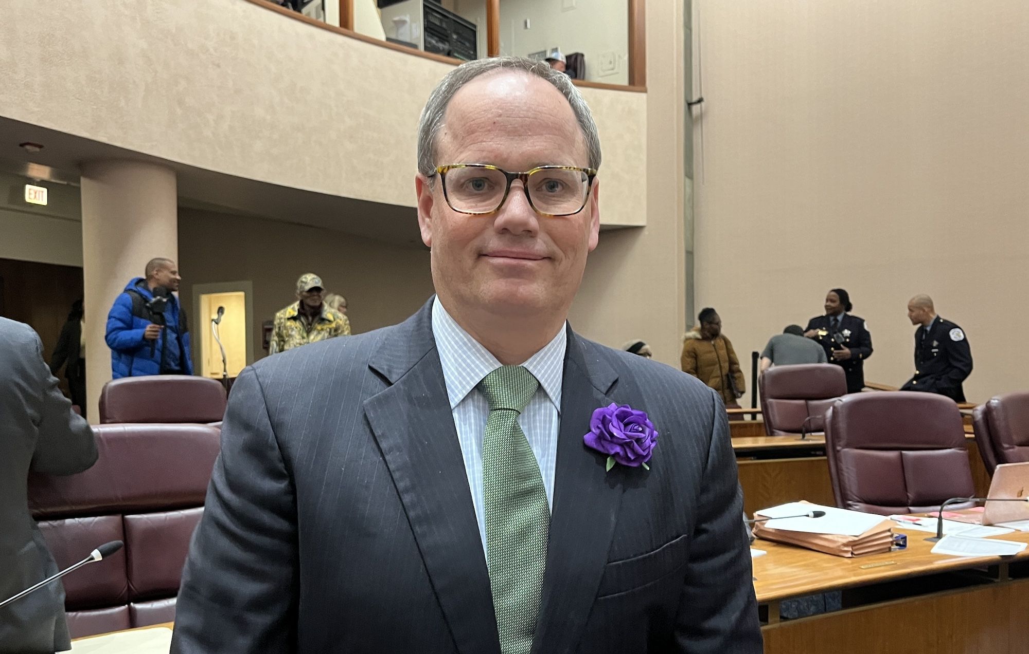 Man in suit wearing purple flower.