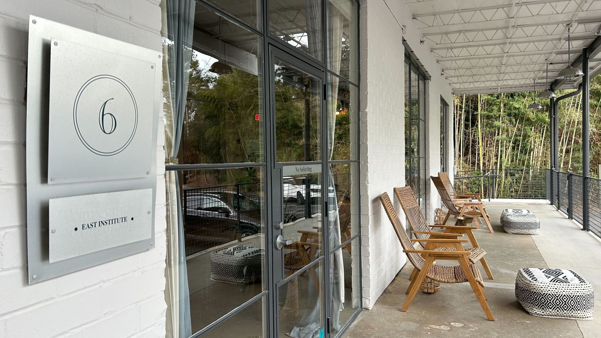 An exterior photo of a loft office with a loading dock patio featuring foot rests and Adirondack-style chairs