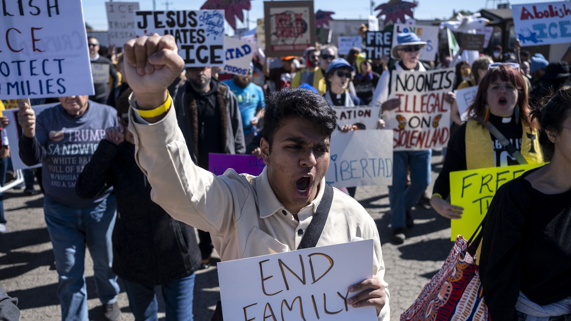 Protestors against ICE marching toward the South Texas Family Residential Center in Dilley, Texas, last month. A man in front holds a fist in the air and a sign that reads "End family..." before it cuts off at the bottom. A sign in the background reads "Abolish ICE."