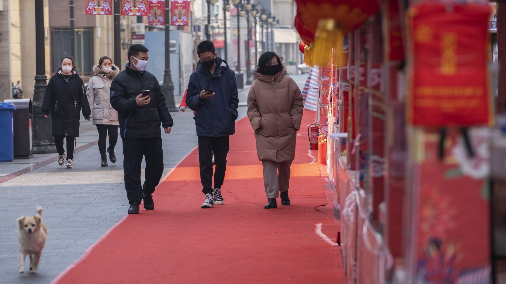  People wearing masks walking passed an empty booth, formerly ready for temple fair and now called off, on the famous business street of Binjiang Dao, China