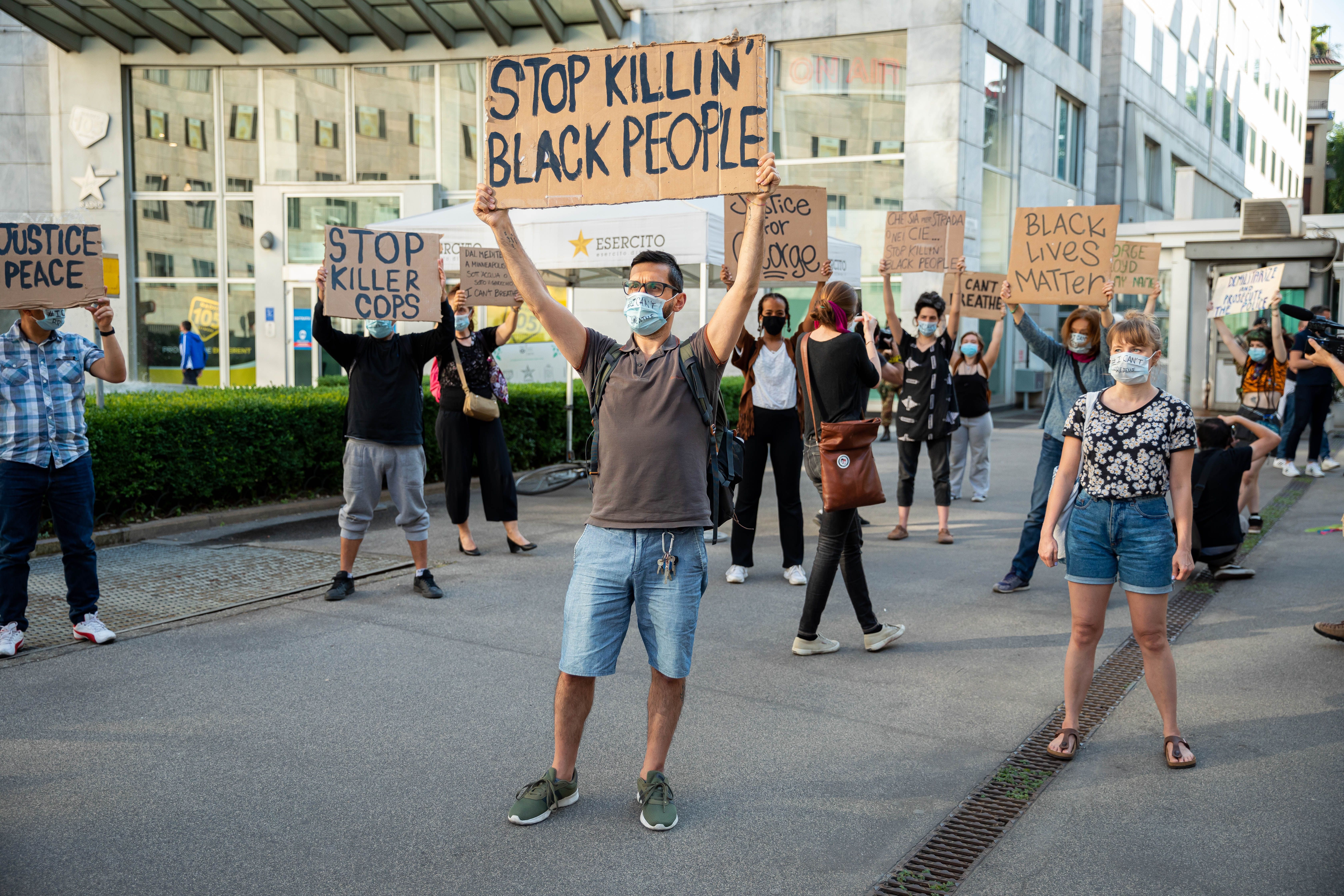 A protest with signs and masks reading I Cant Breath, following George Floyd's death in front of the consulate