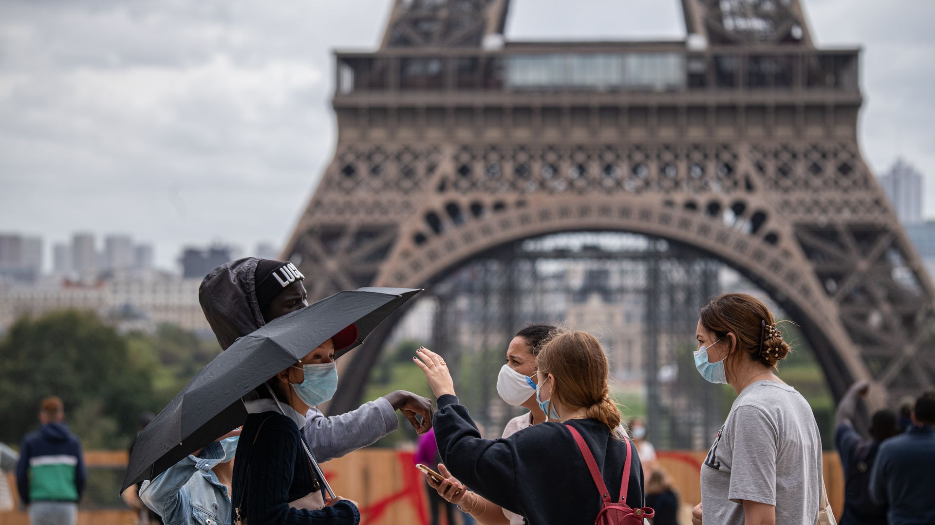 People wear masks in Paris by the Eiffel Tower.