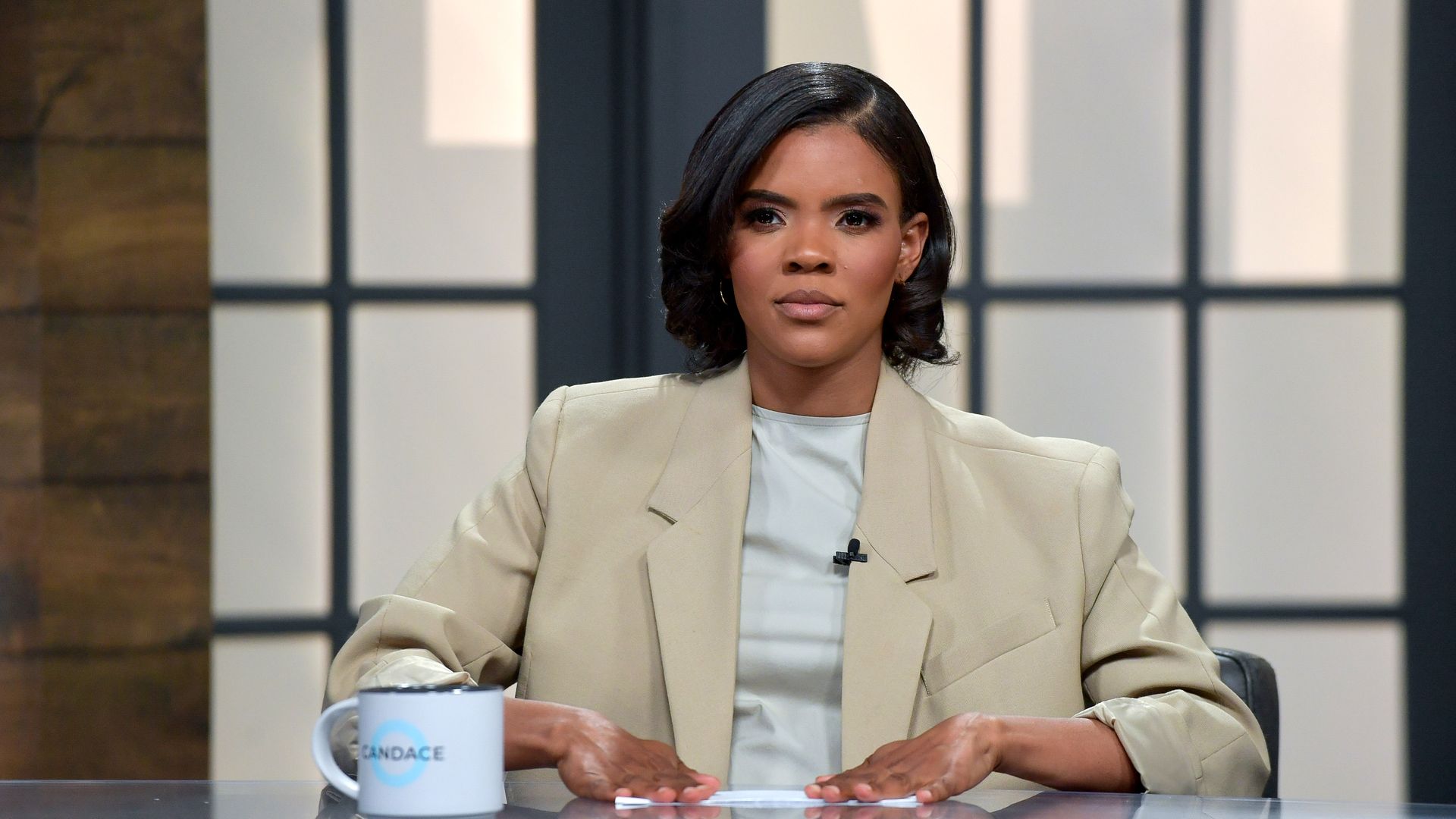 Candace Owens sits at a desk. 