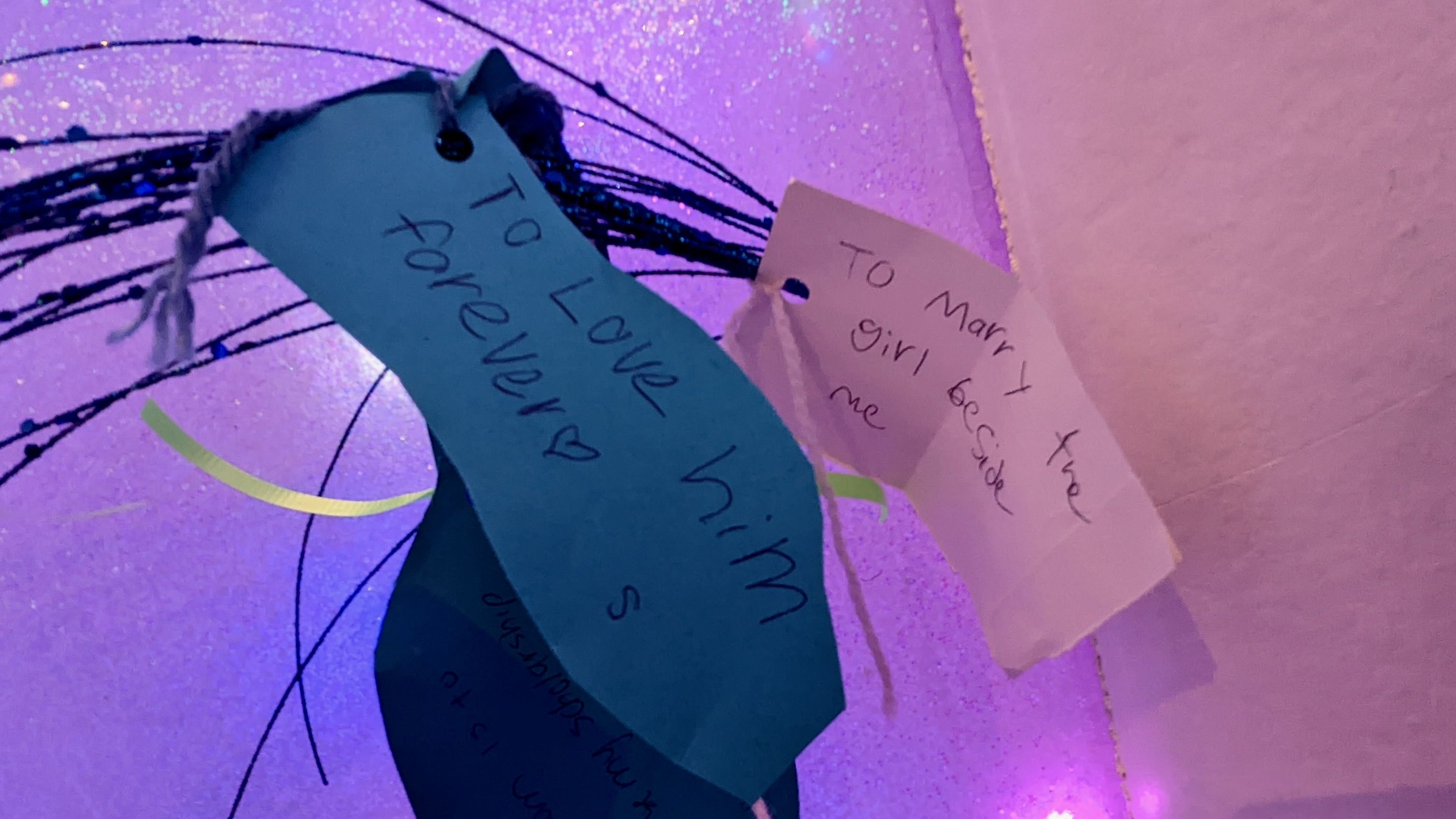 A paper reads "To marry the girl beside me" and the paper next to it reads "to love him forever."