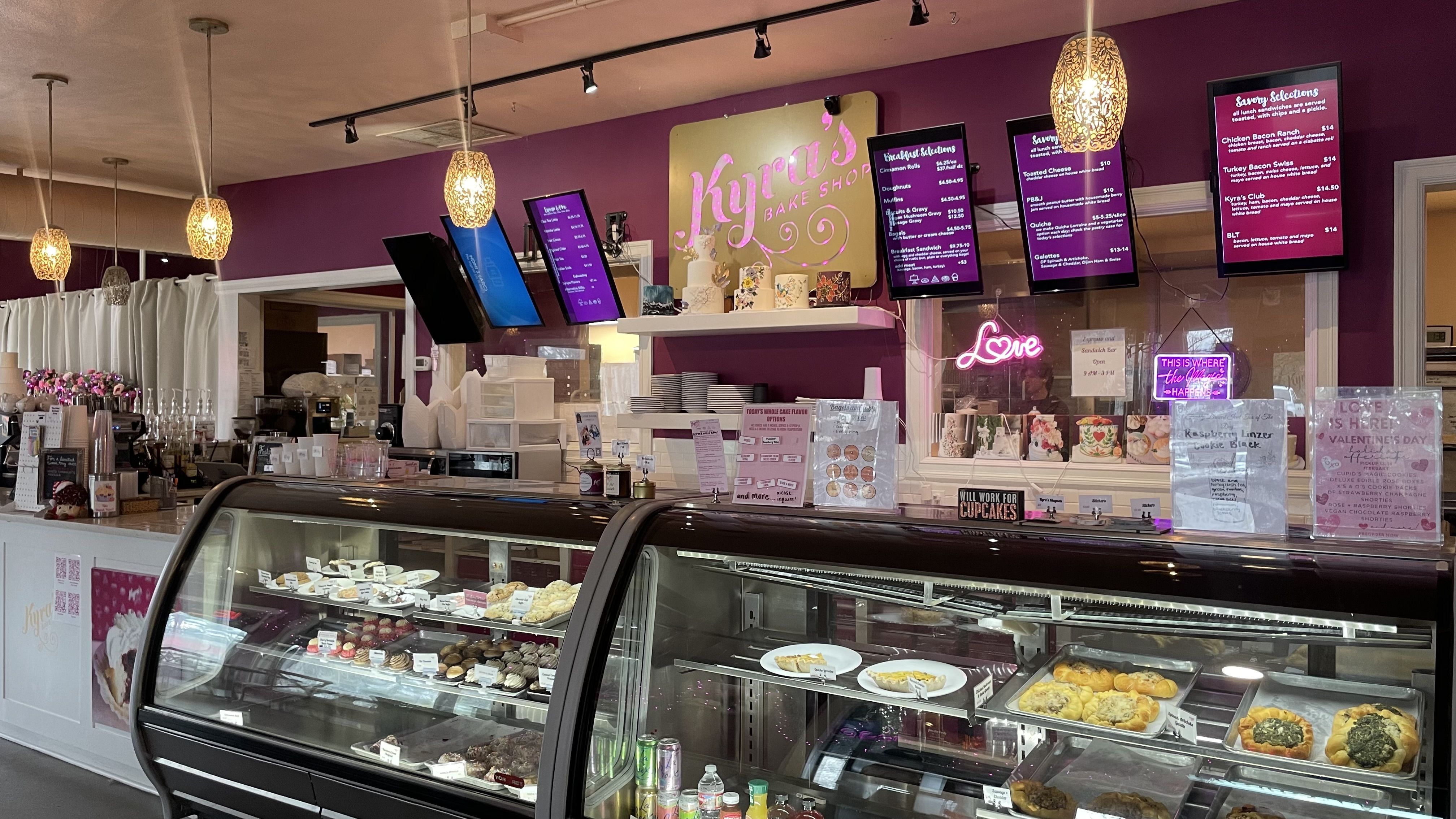 A photo of a pastry case inside a restaurant with a pink sign that says "Kyra's"