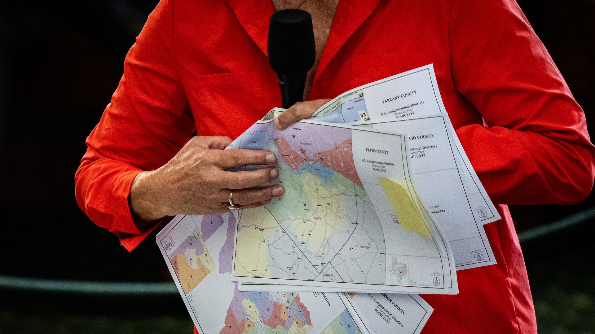 Texas Sen. Sarah Eckhardt (D-Austin) is seen holding a then-proposed congressional map in August. The photo does not show her head. She is dressed in a red suit.