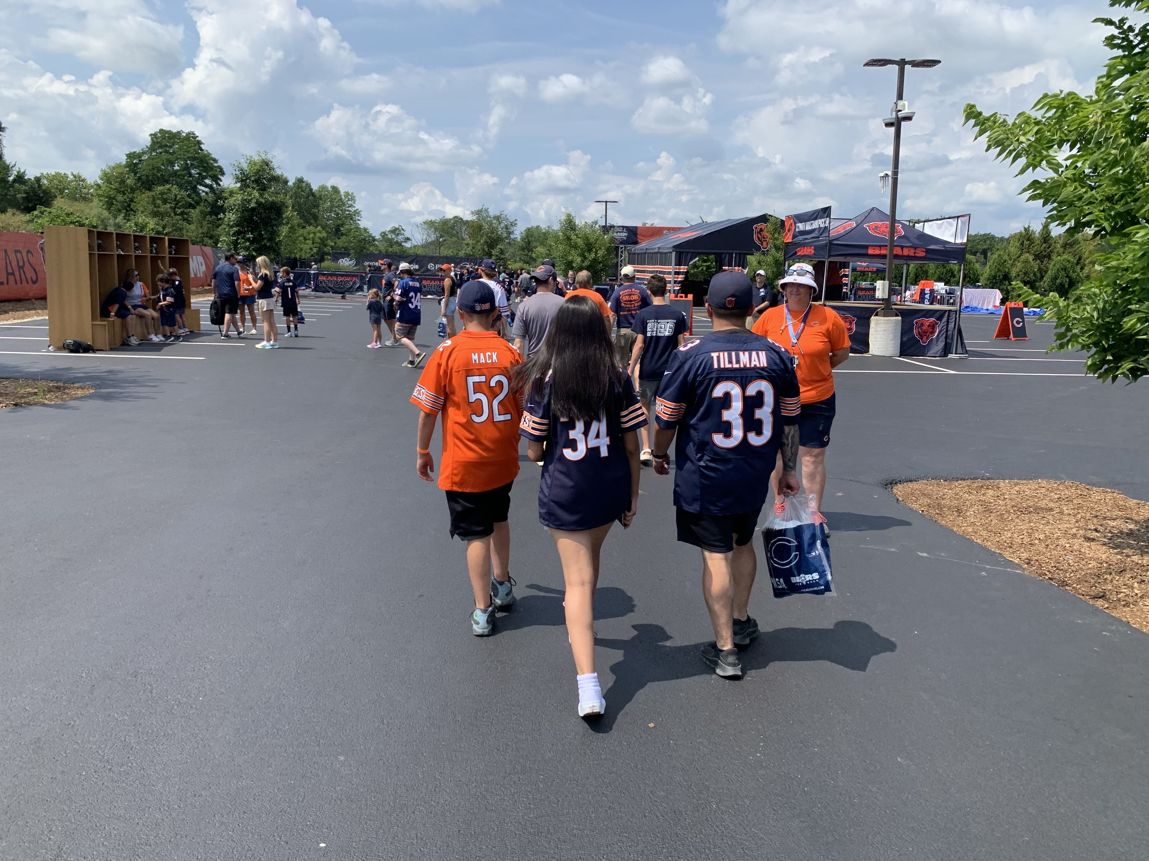 Photo of football fans in jerseys walking around parking lot festival 