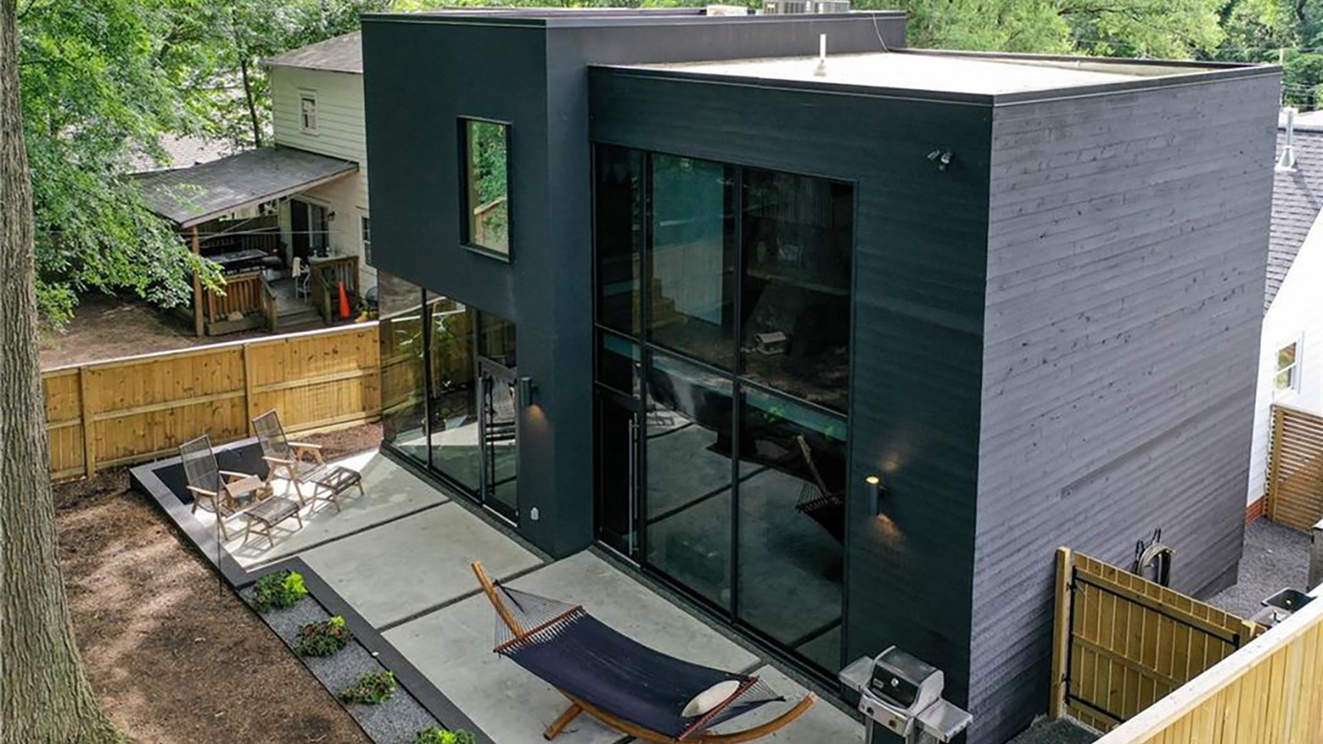the back of a house in Wilmore, black with windows covering two stories on the backside and a hammock on a patio