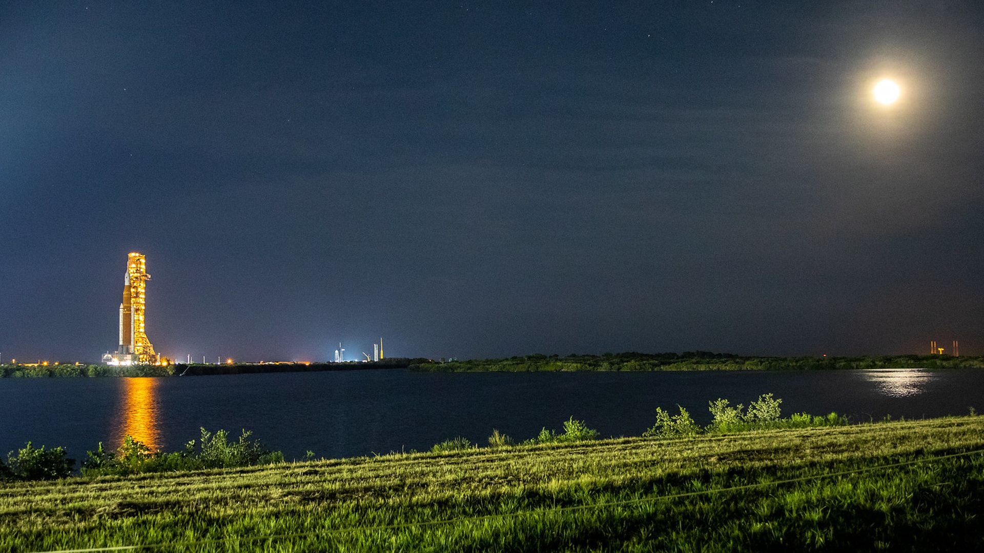 The Space Launch System rocket waiting for launch with the Moon bright to the right