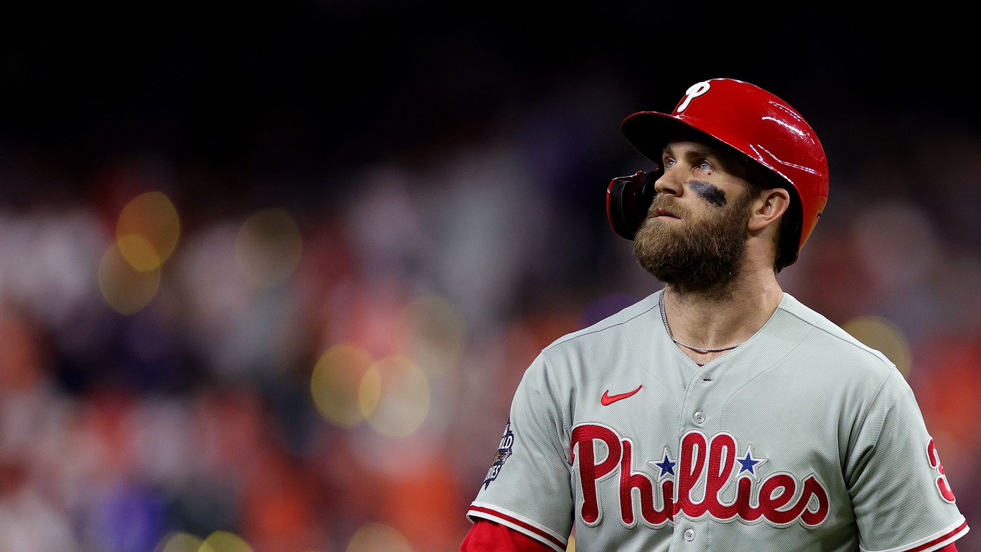 Bryce Harper stares off into the distance in front of a blurred crowd.