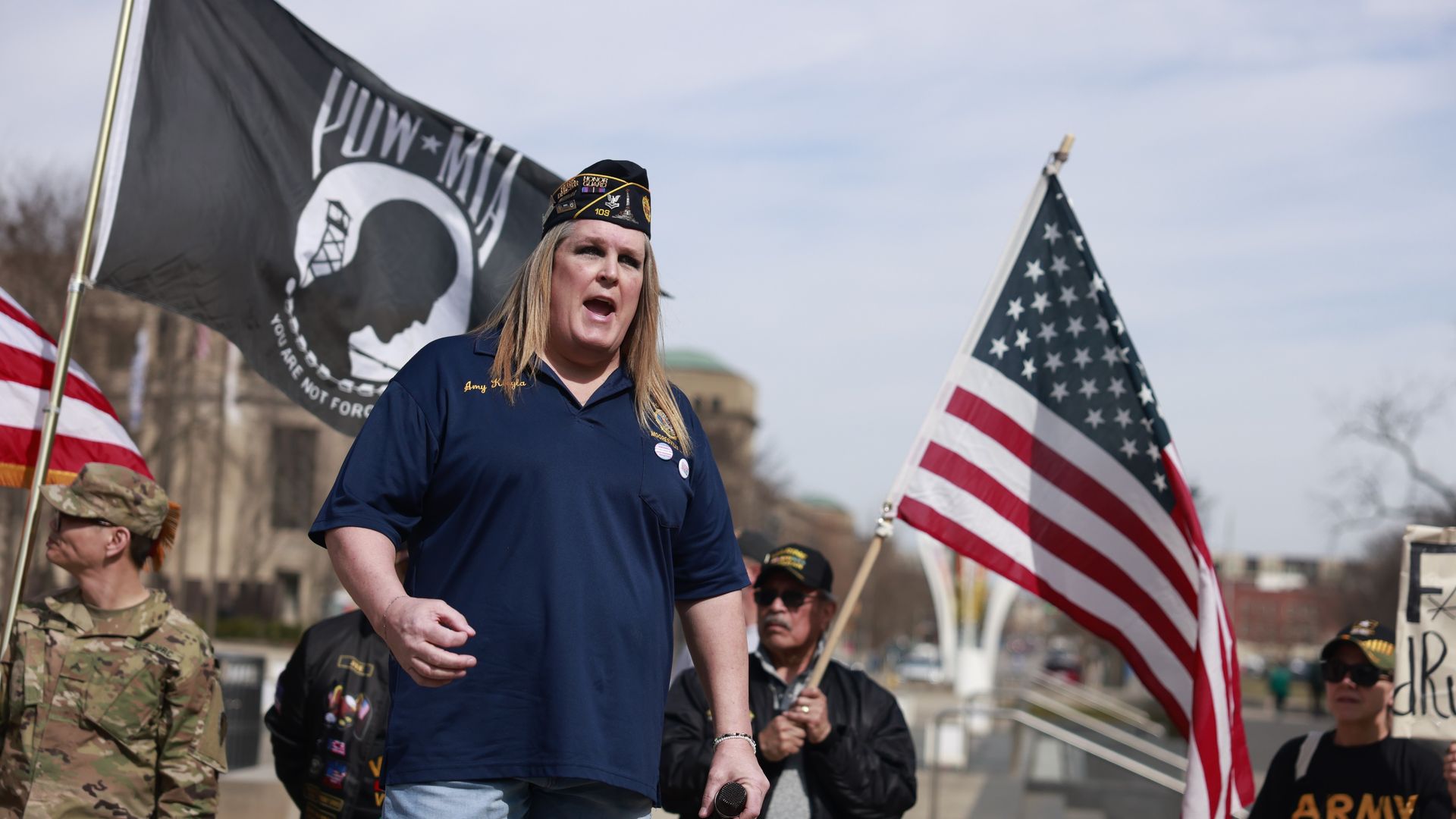 Person speaks while others hold flags in background