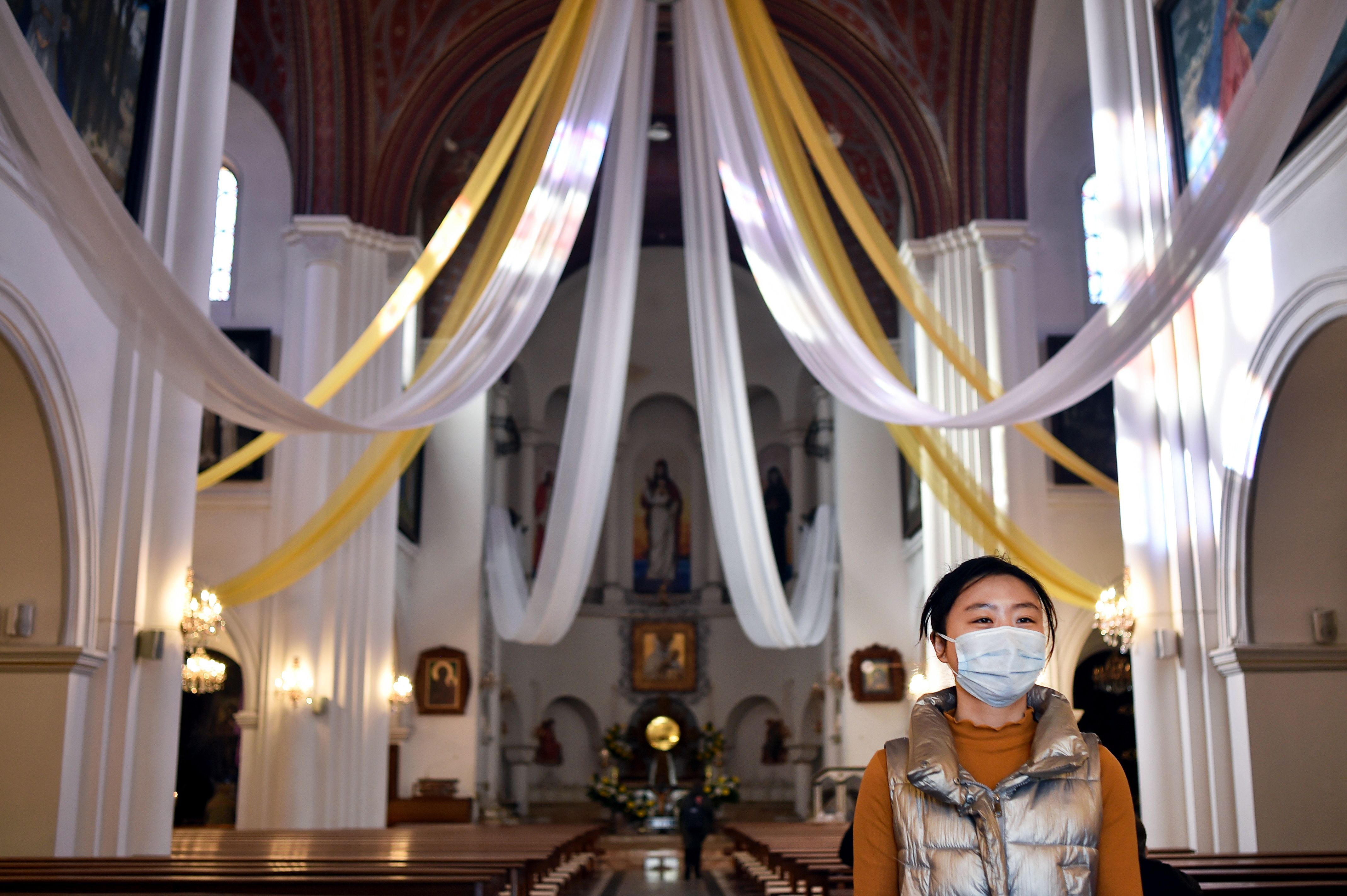 A woman wears a mask in a cathedral in this image