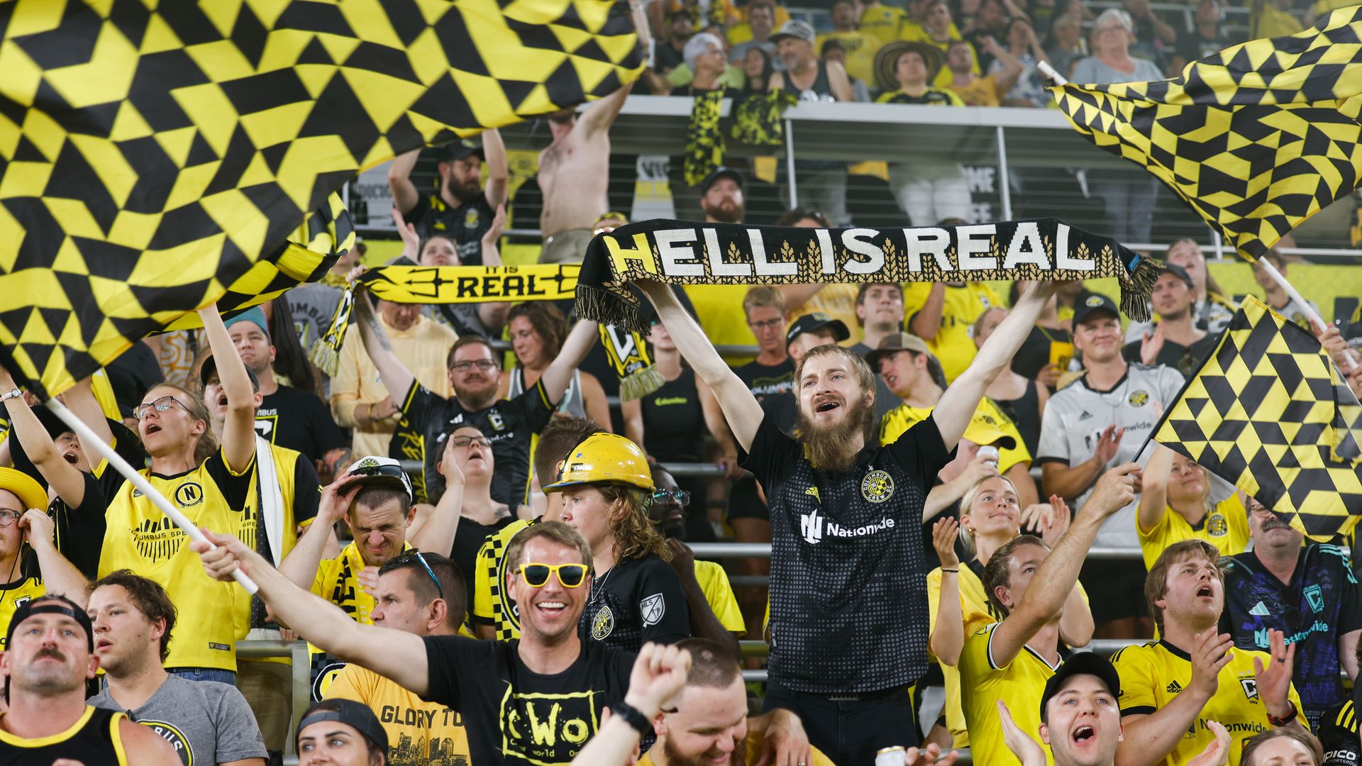 Columbus Crew fans wave banners and hold a "Hell Is Real" scarf