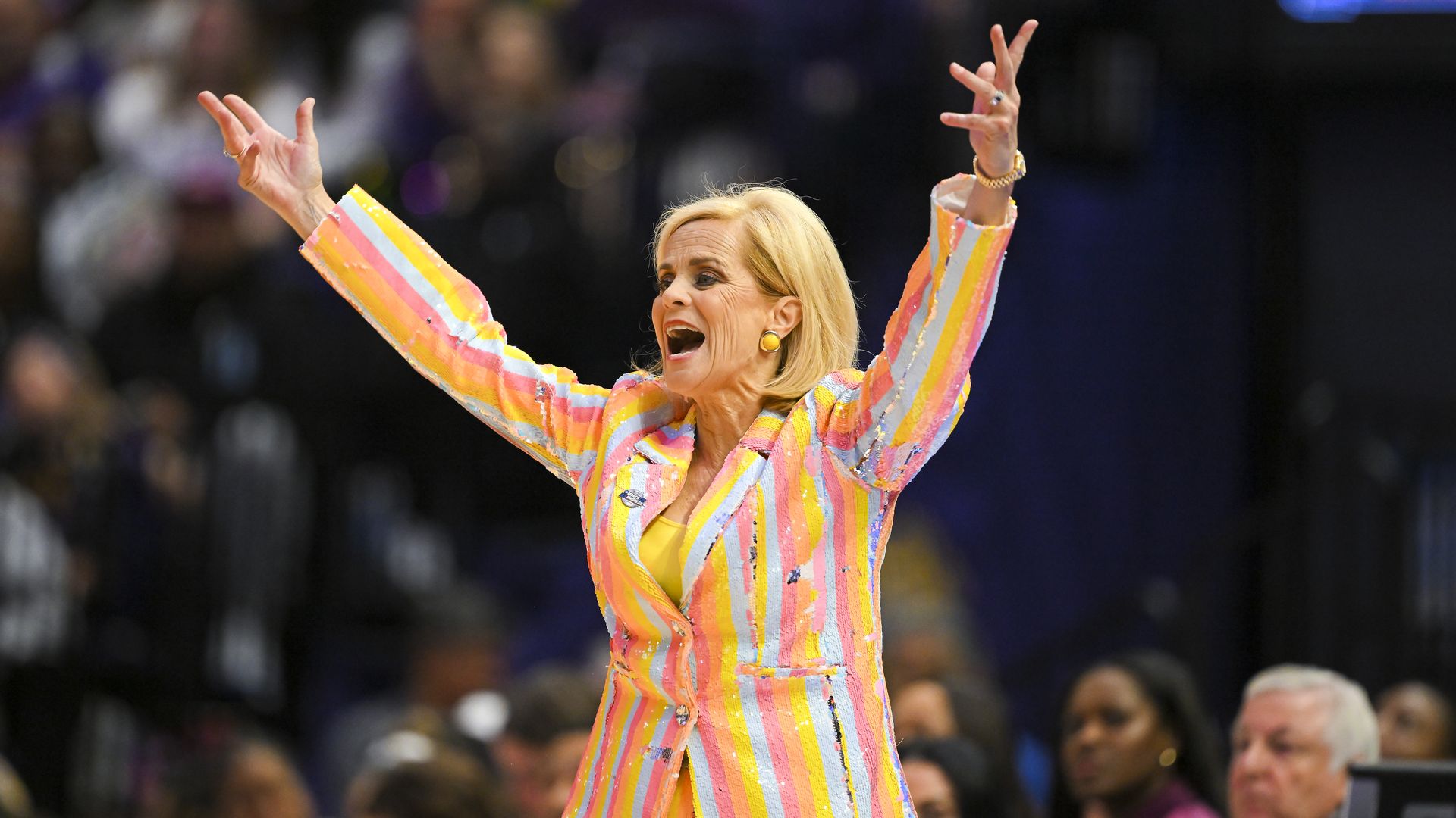 Photo shows LSU women's basketball coach Kim Mulkey in a colorful striped suit.