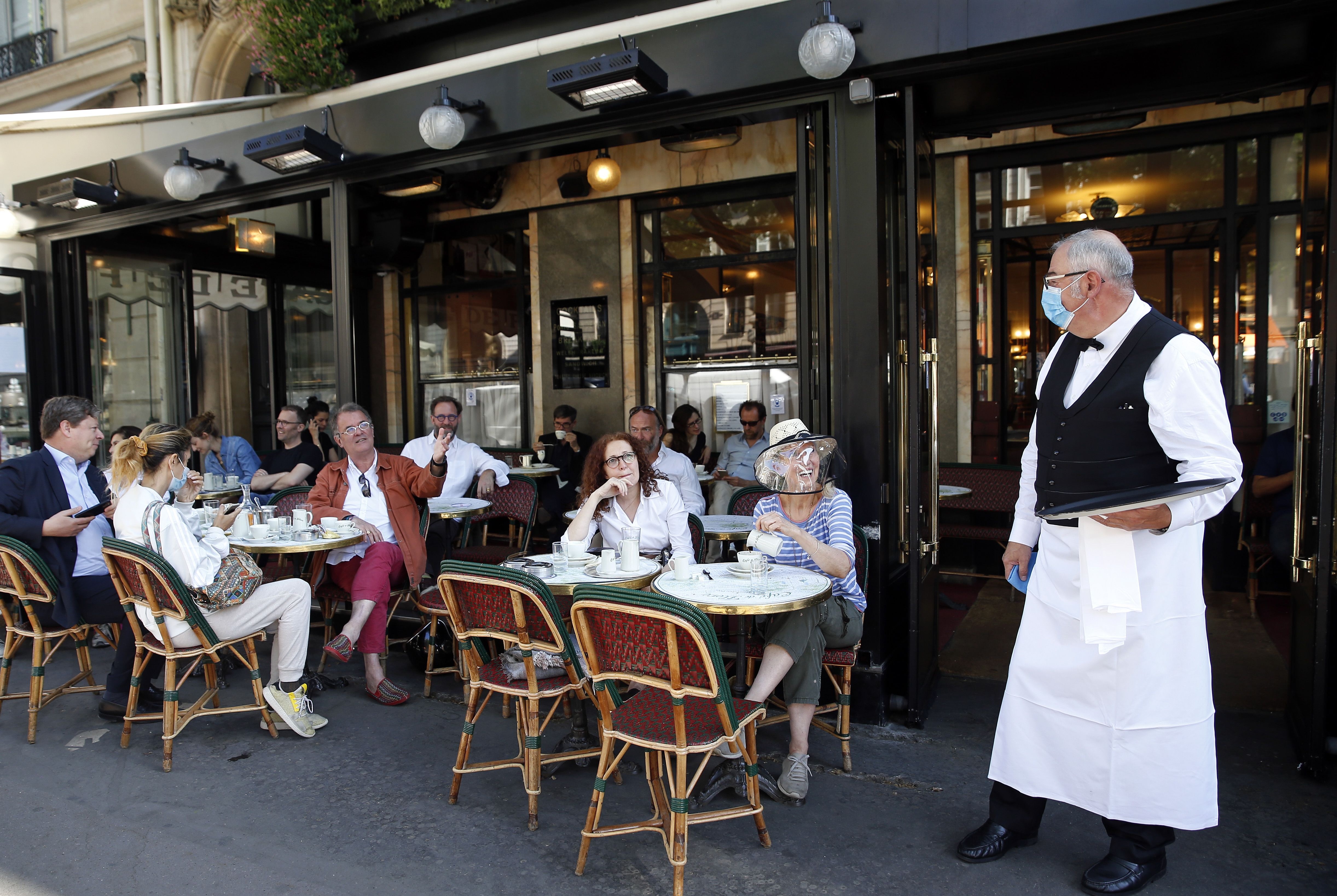 A waiter wearing a protective face mask serves at the terrace of 'Cafe de Flore' in the Latin Quarter district as bars and restaurants reopen 