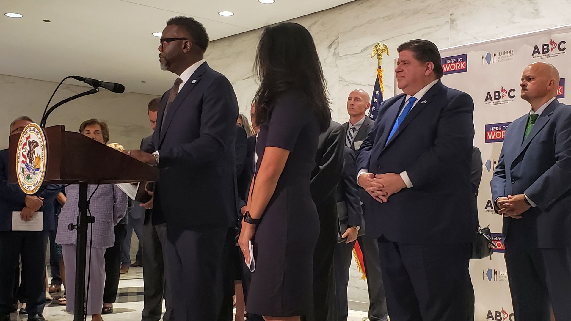Brandon Johnson stands at a podium, with Gov. JB Pritzker behind him.