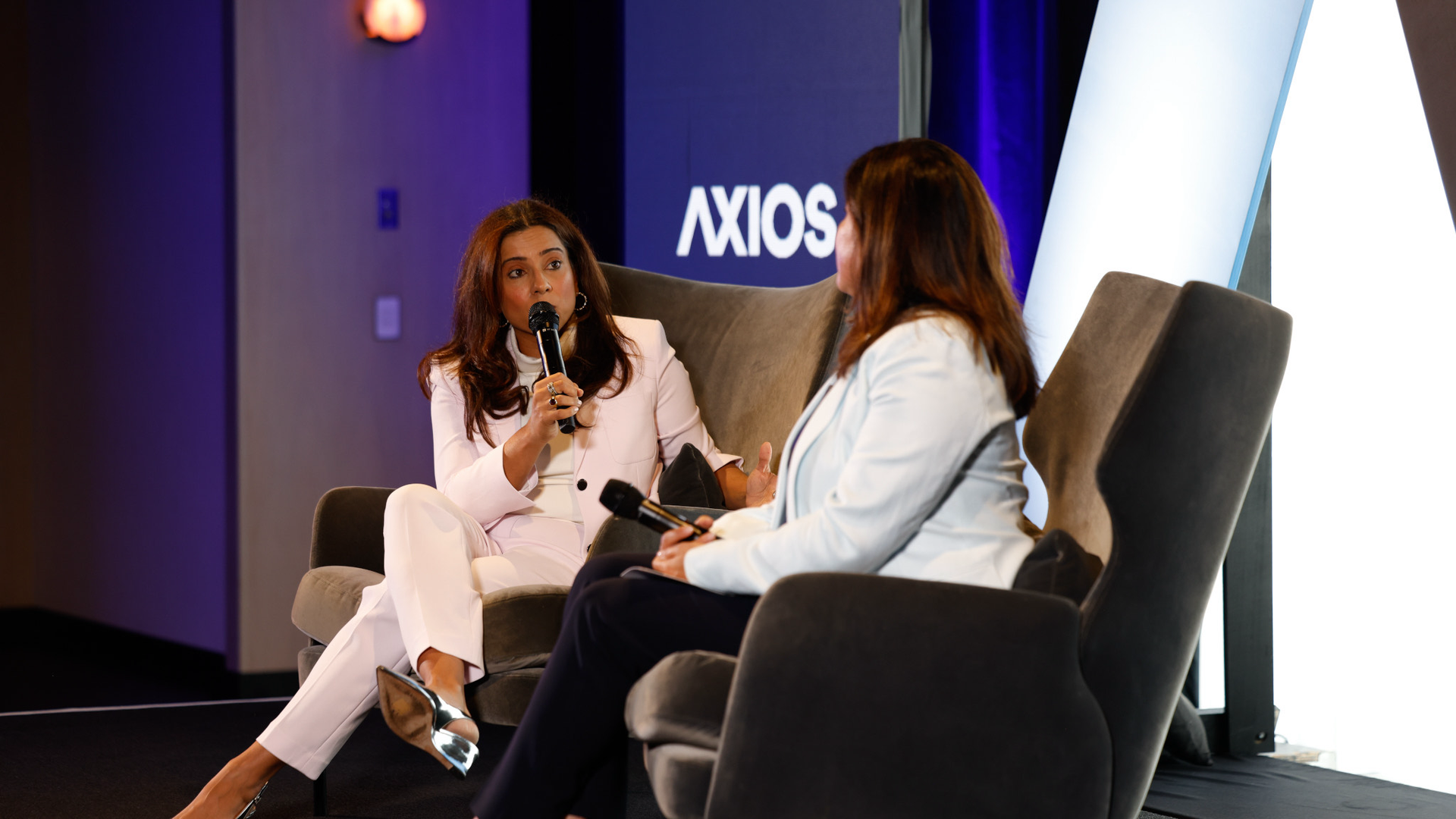 Two women sitting in chairs talking on a stage