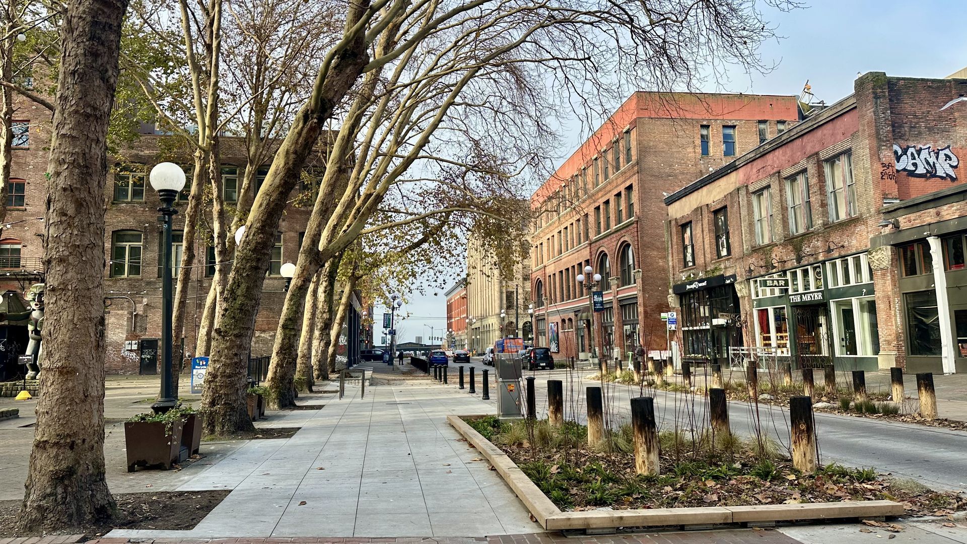 A view of pedestrian improvements on South Washington street, including wider sidewalks, green plantings and burned piers to represent the Great Seattle Fire.