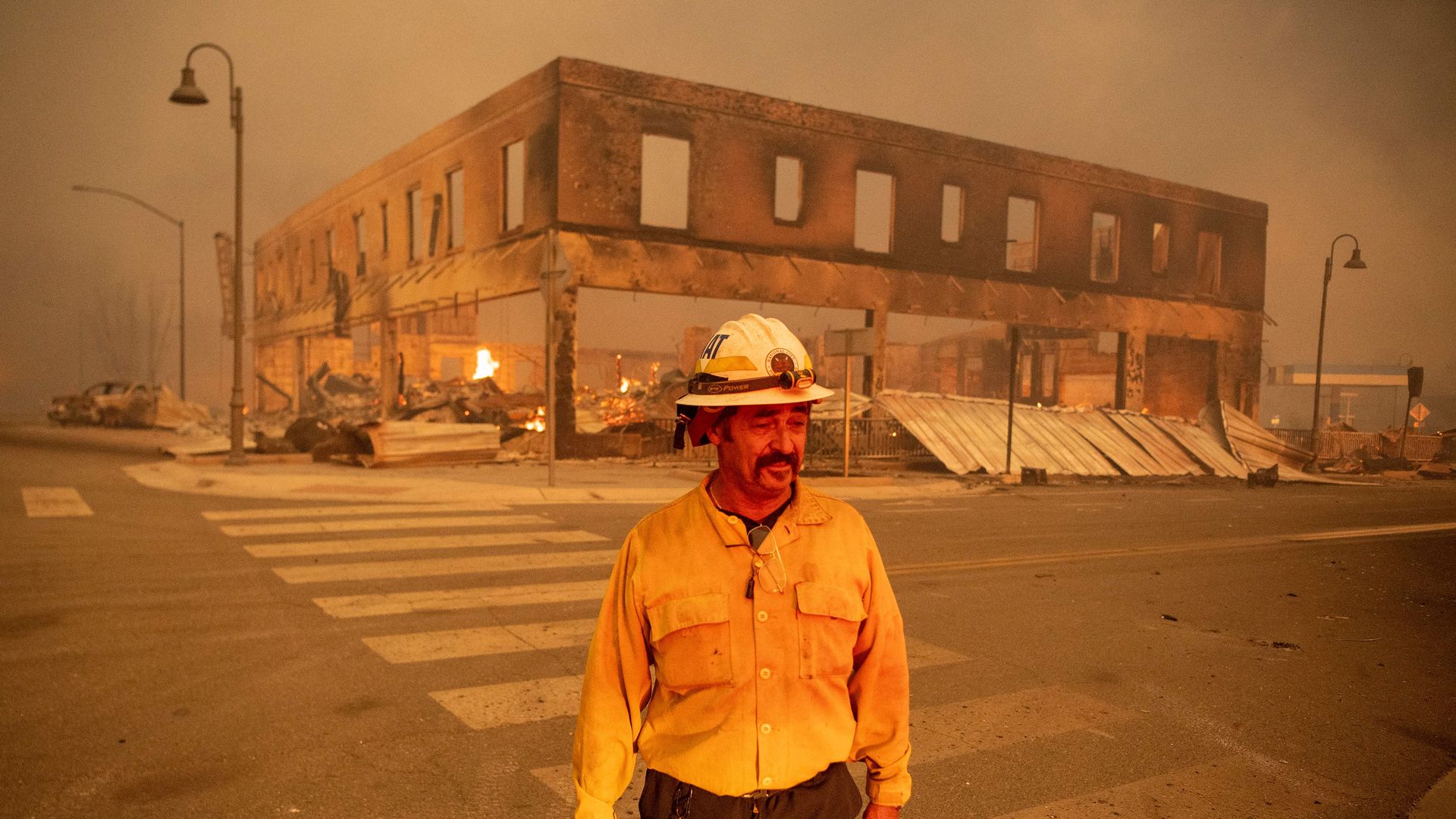 Firefighter standing in front of a burned out historic building.