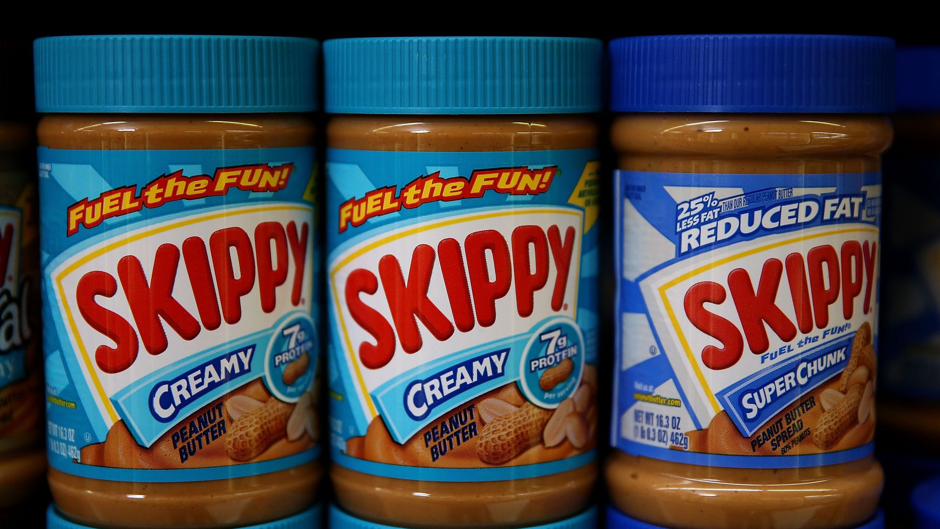 Jars of Skippy peanut butter are displayed on a shelf at a store