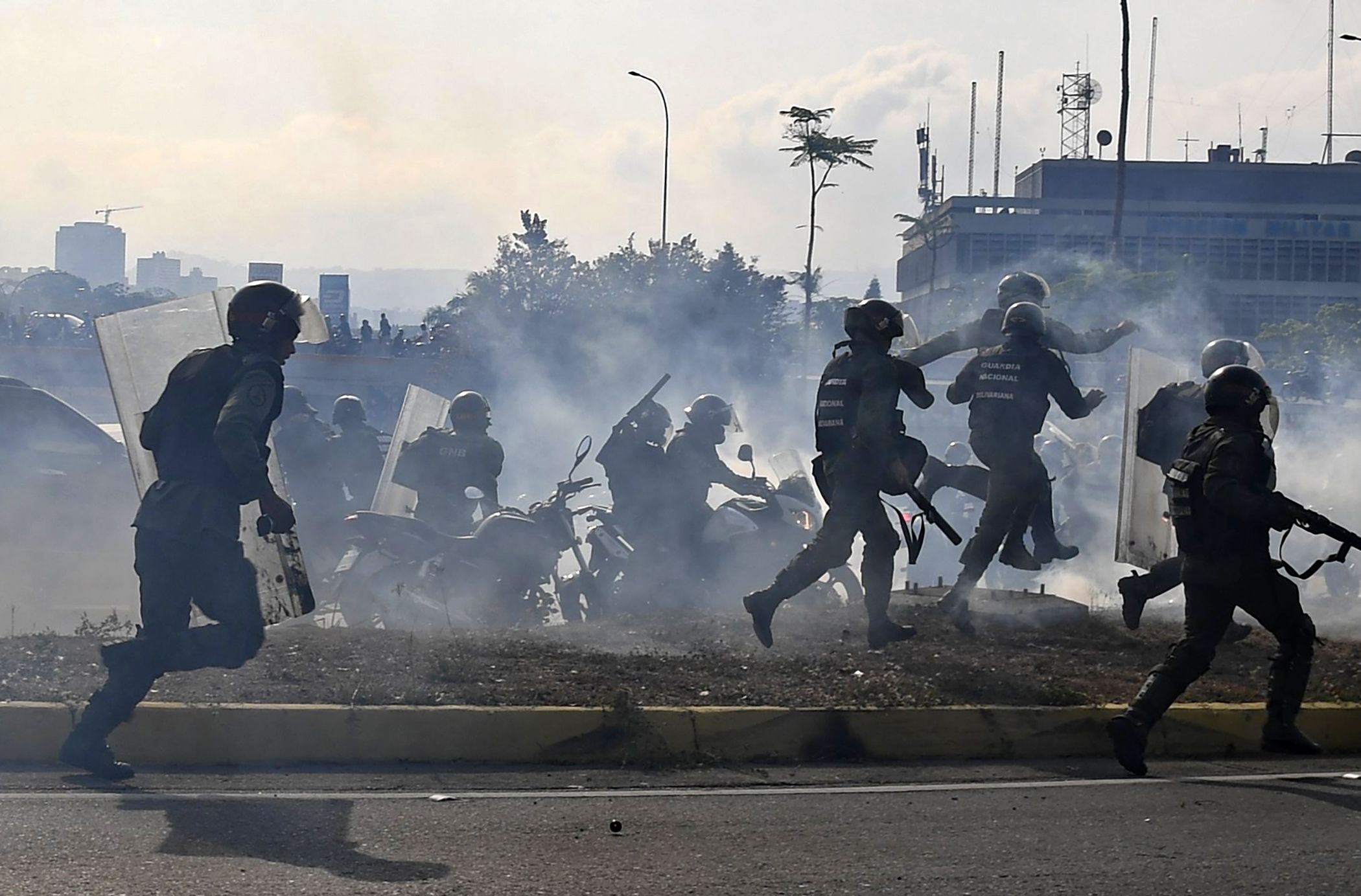  Members of the Bolivarian National Guard loyal to Venezuelan President Nicolas Maduro run under a cloud of tear gas.