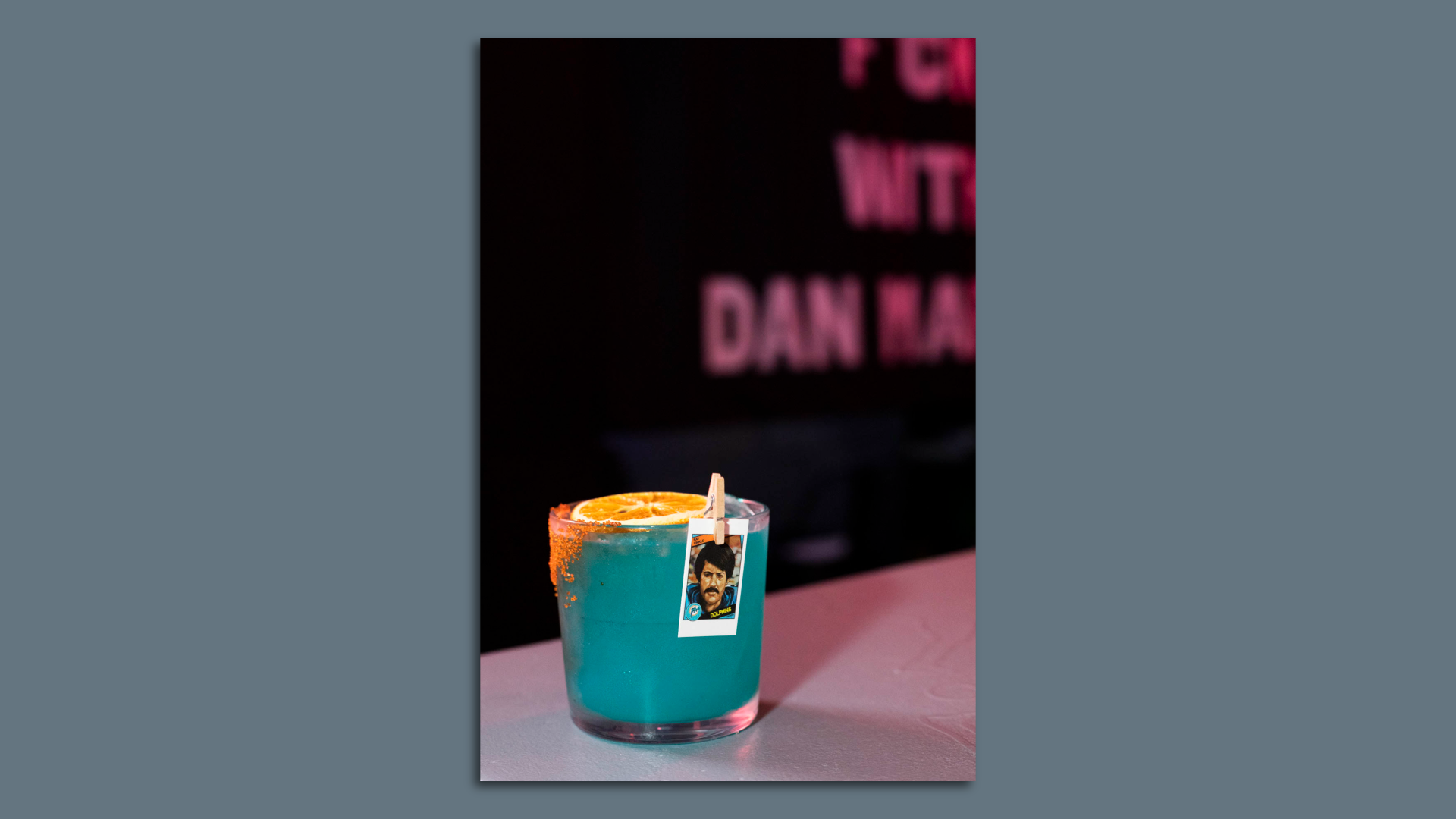 A blue drink with an orange garnish and a photo of Ray Finkle 