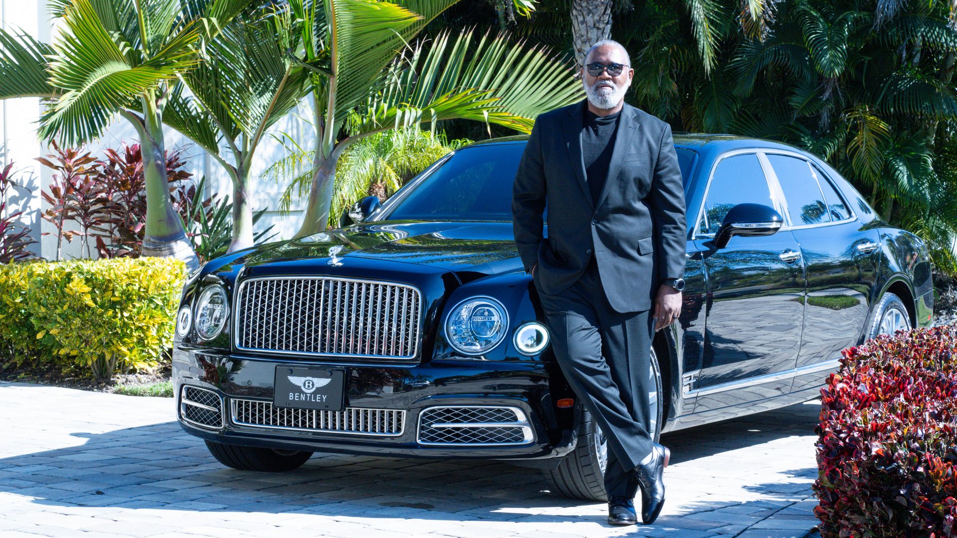 A chauffeur in front of a Bentley