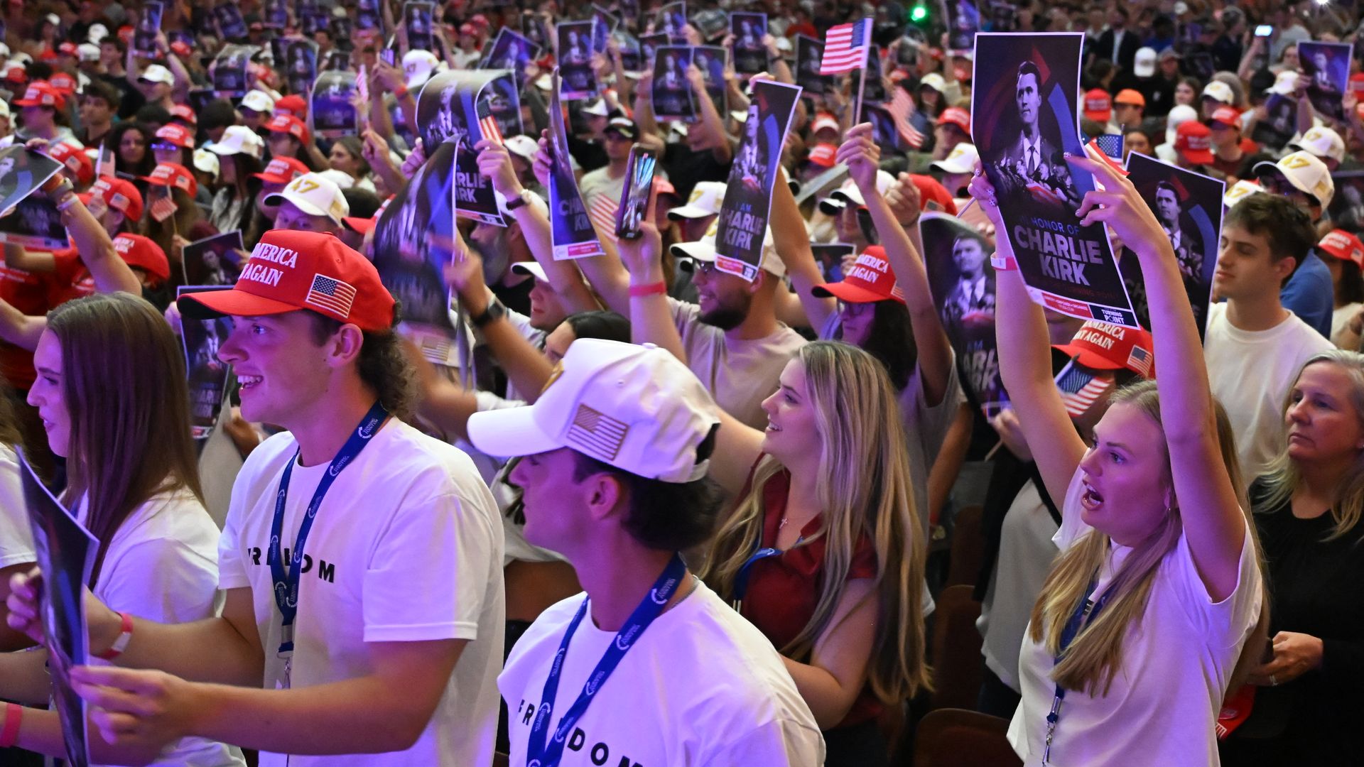 a crowd of students wearing MAGA hats and holding Kirk posters 
