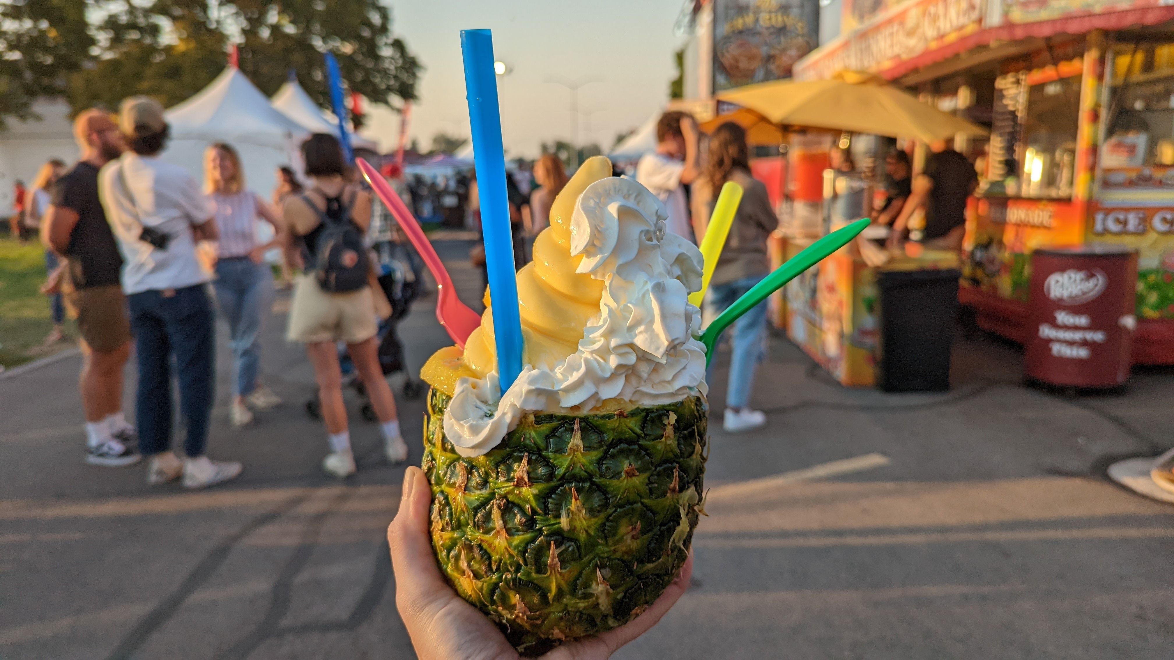 A pineapple is hollowed out to hold ice cream at a carnival.