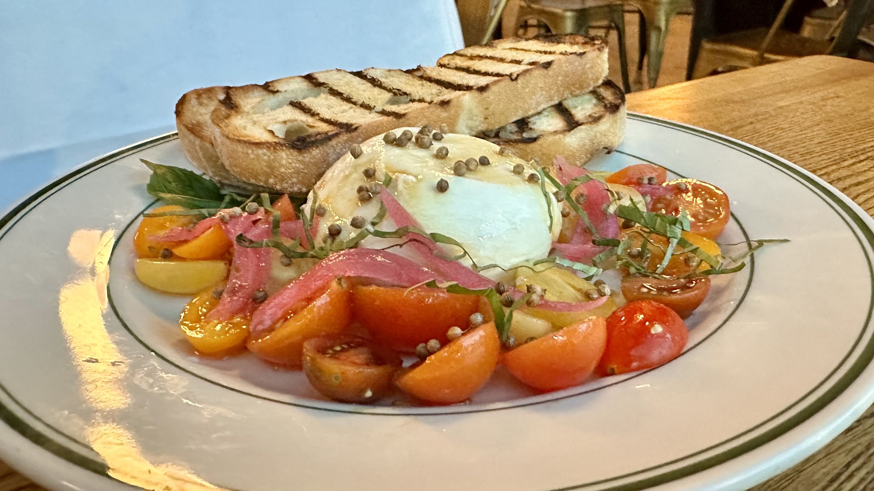 A photo of a plate of tomatoes and burrata