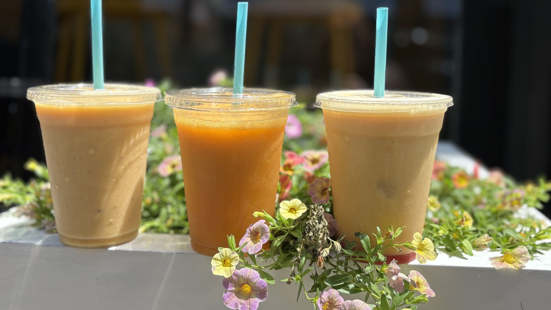Smoothies surrounded by pink and yellow flowers.
