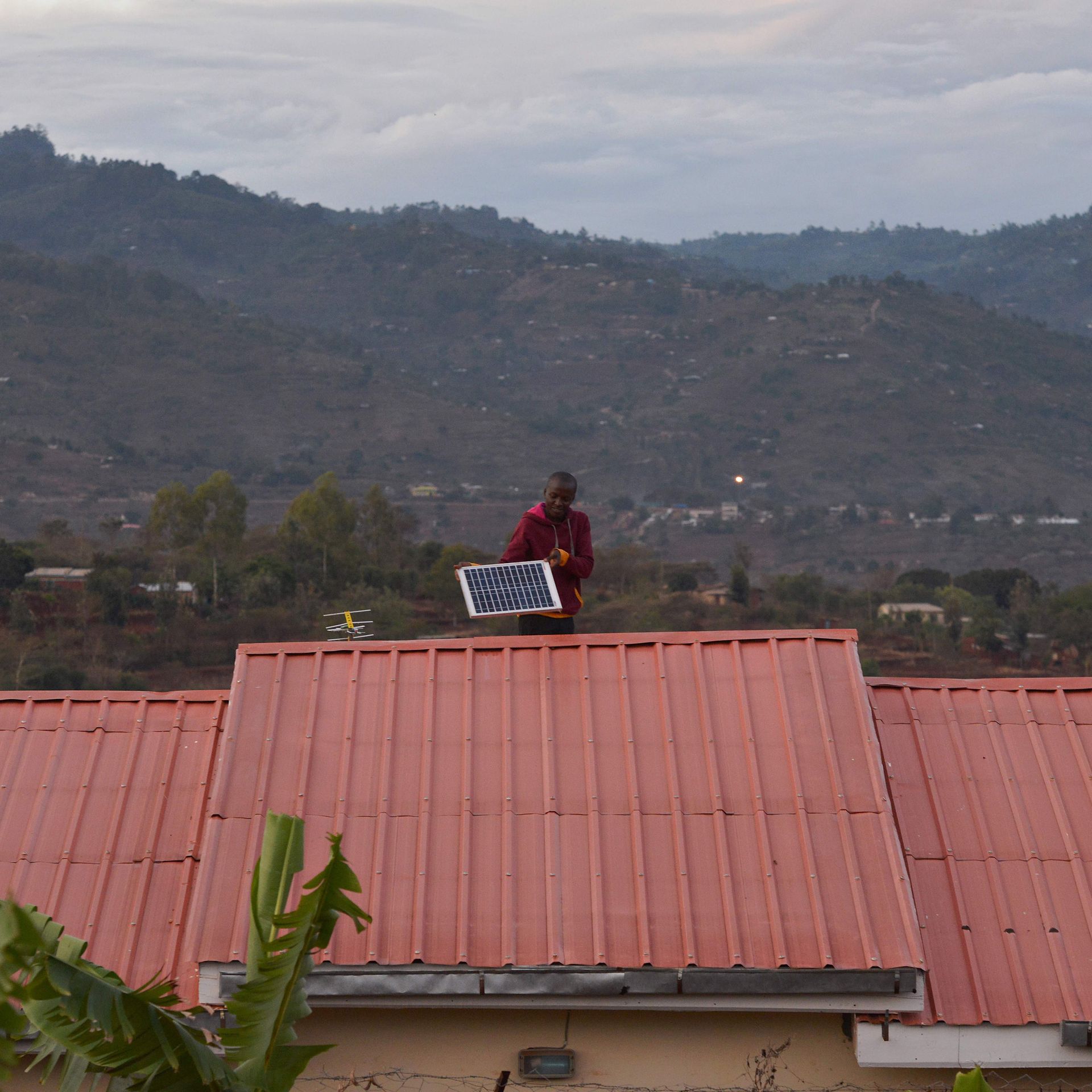 A man adjusts a solar panel on his roof at dusk in the villqge of Kwa-Mutisya in Machakos county, some 100 kilometres southeast of Nairobi, on November 16, 2016. 