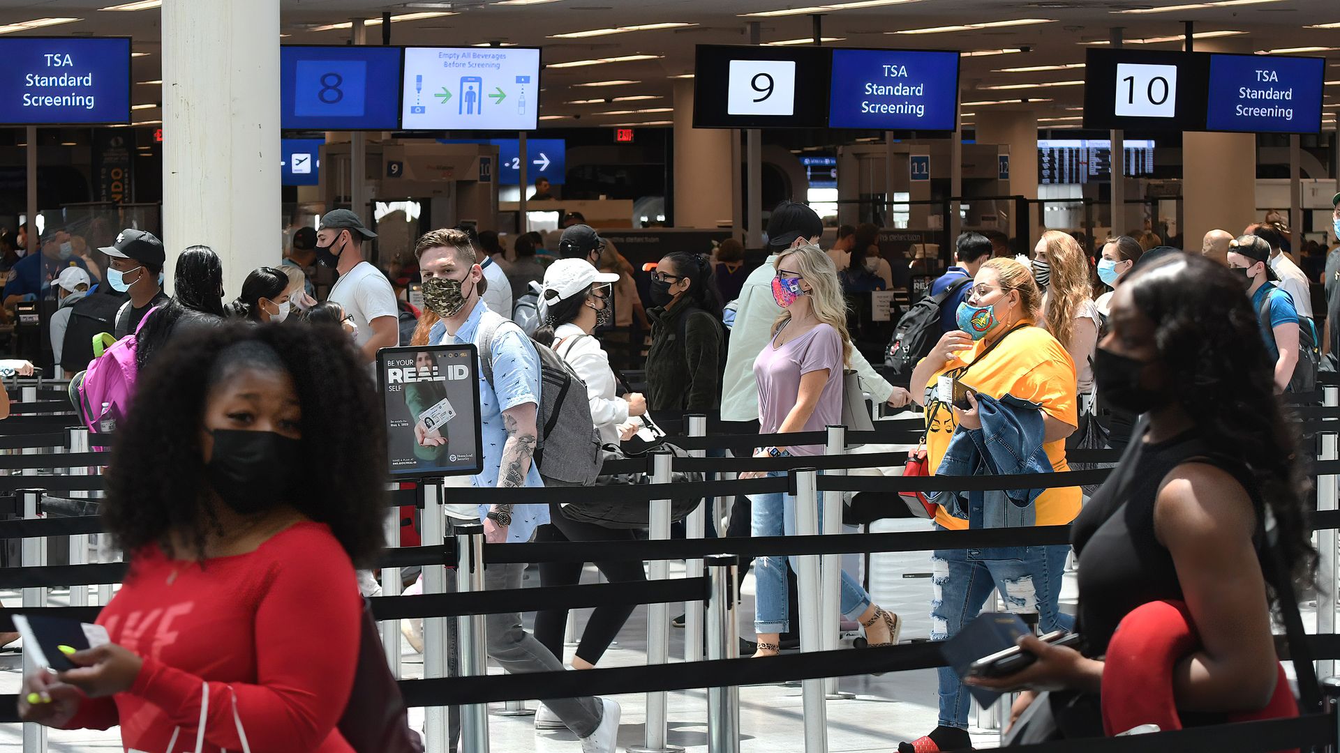 Picture of travelers wearing masks waiting in line at a TSA screening checkpoint