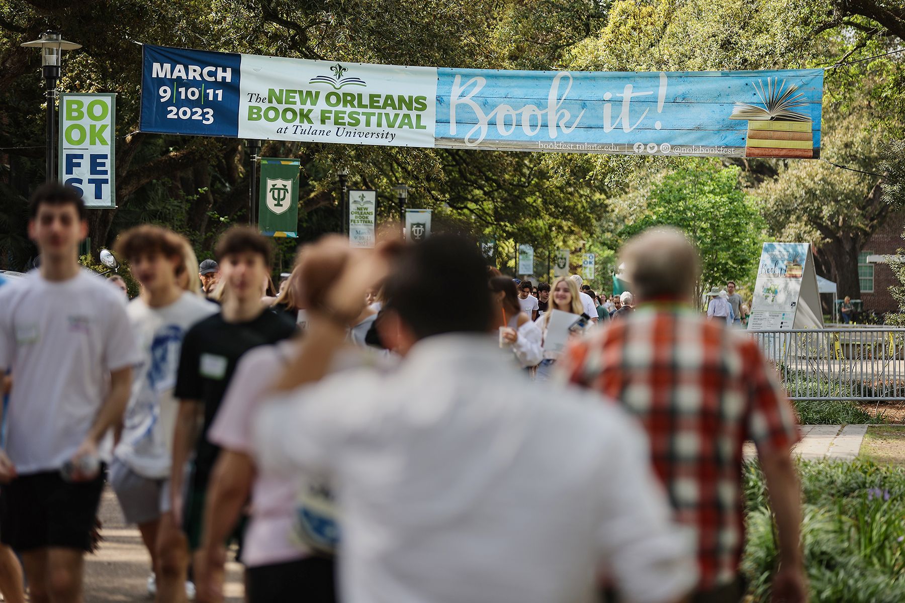 People walk under a banner that says New Orleans Book Festival.